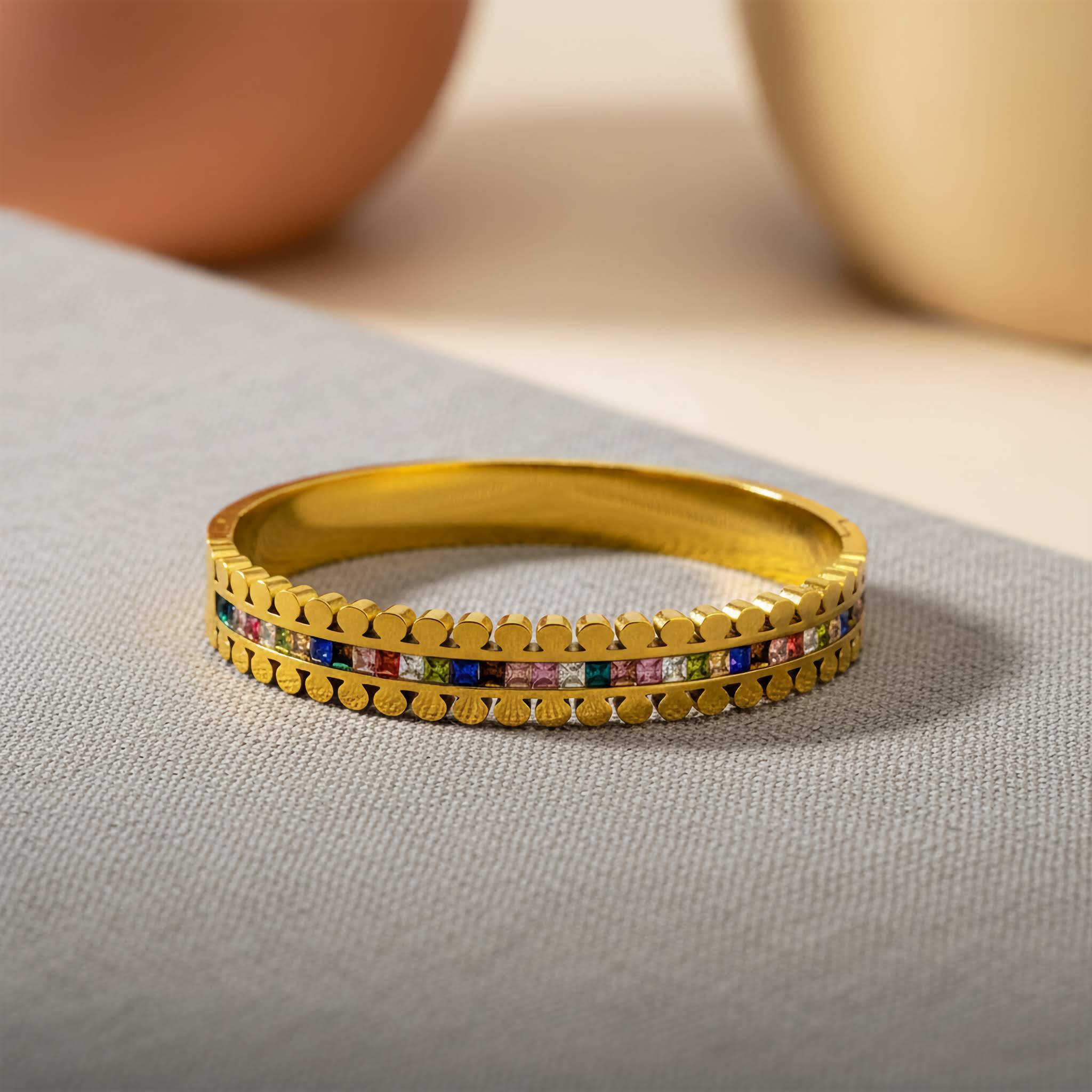 Gold bangles with colorful stones on a neutral background