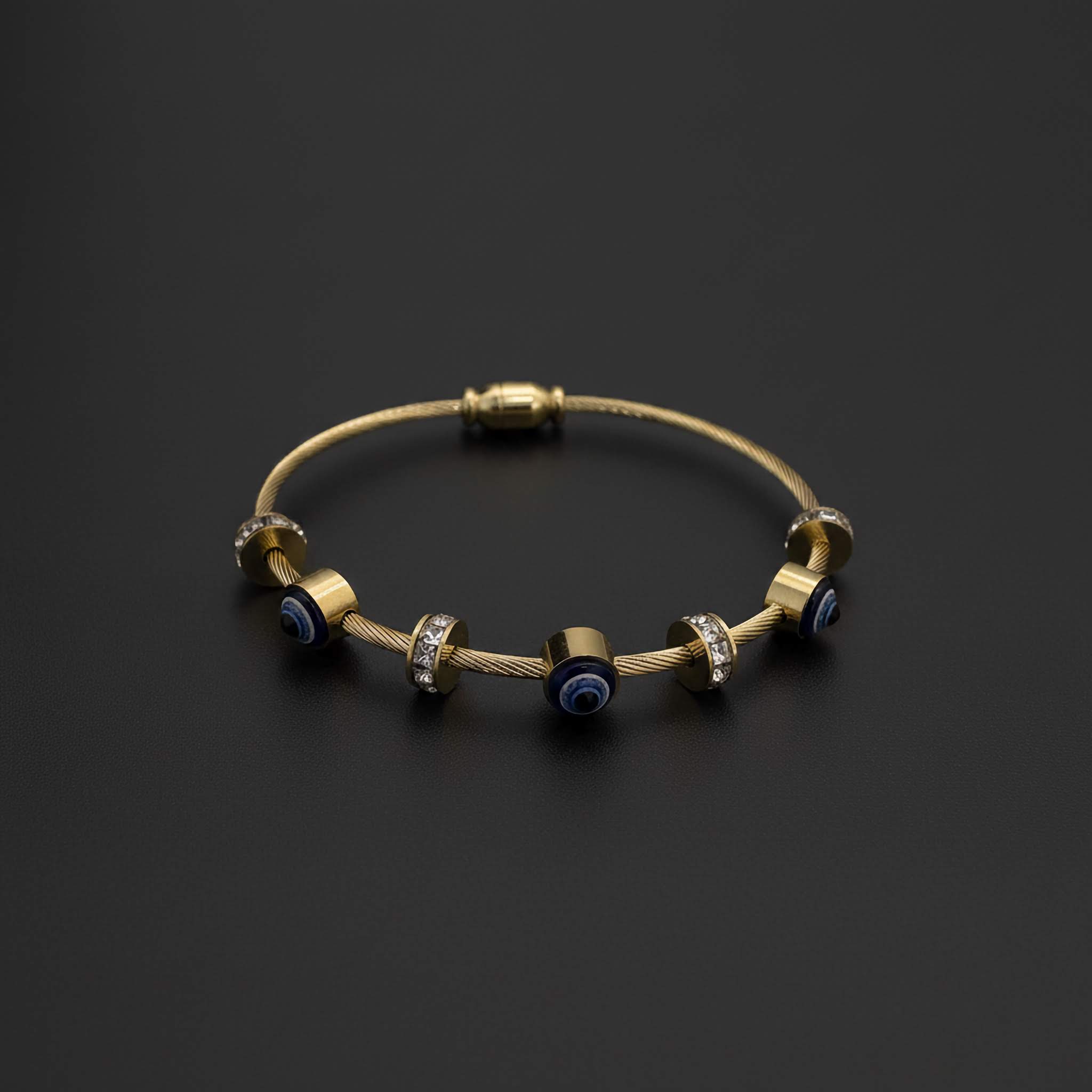 Gold bracelet with blue evil eye charms on a black background