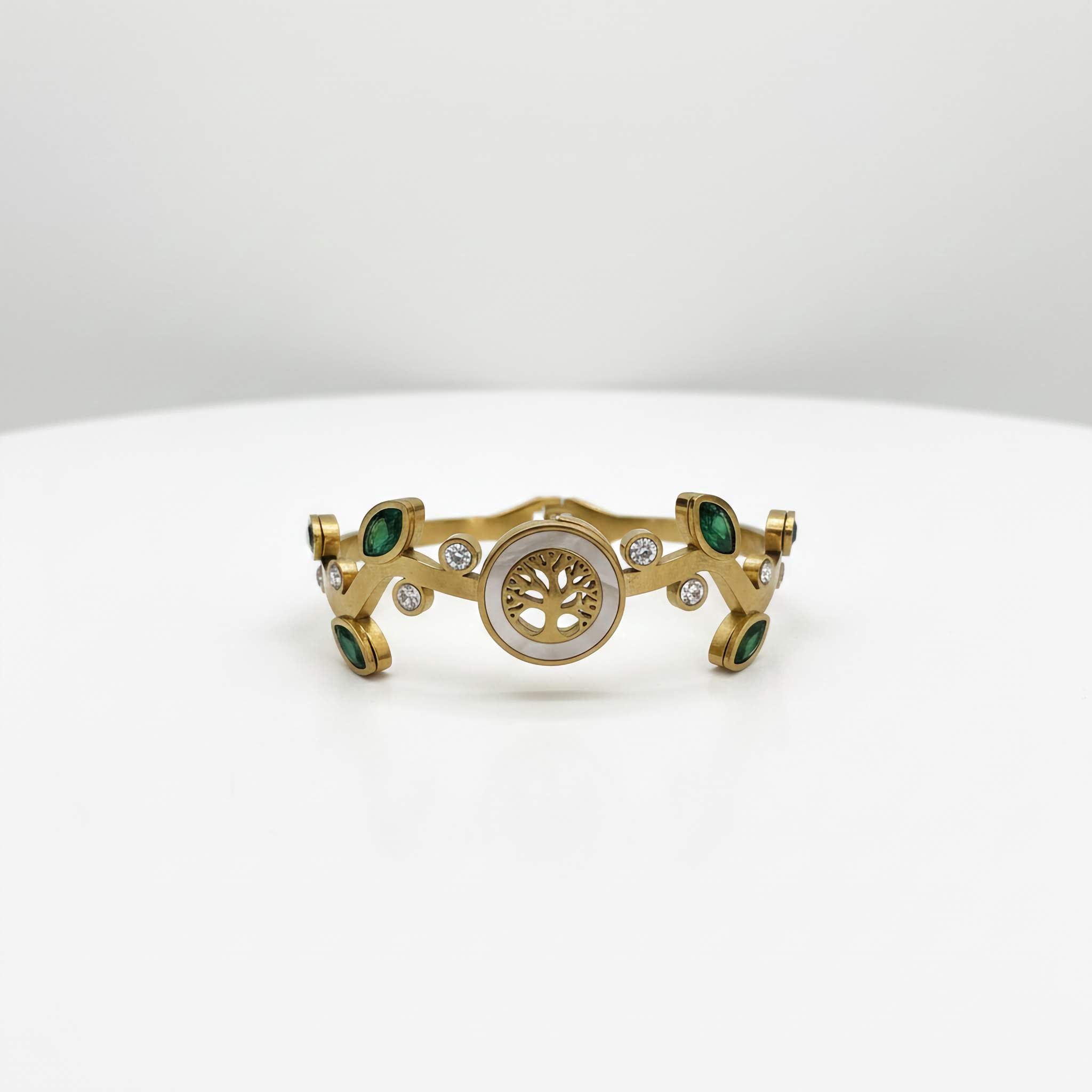 Gold bracelet with green gemstones on a white background