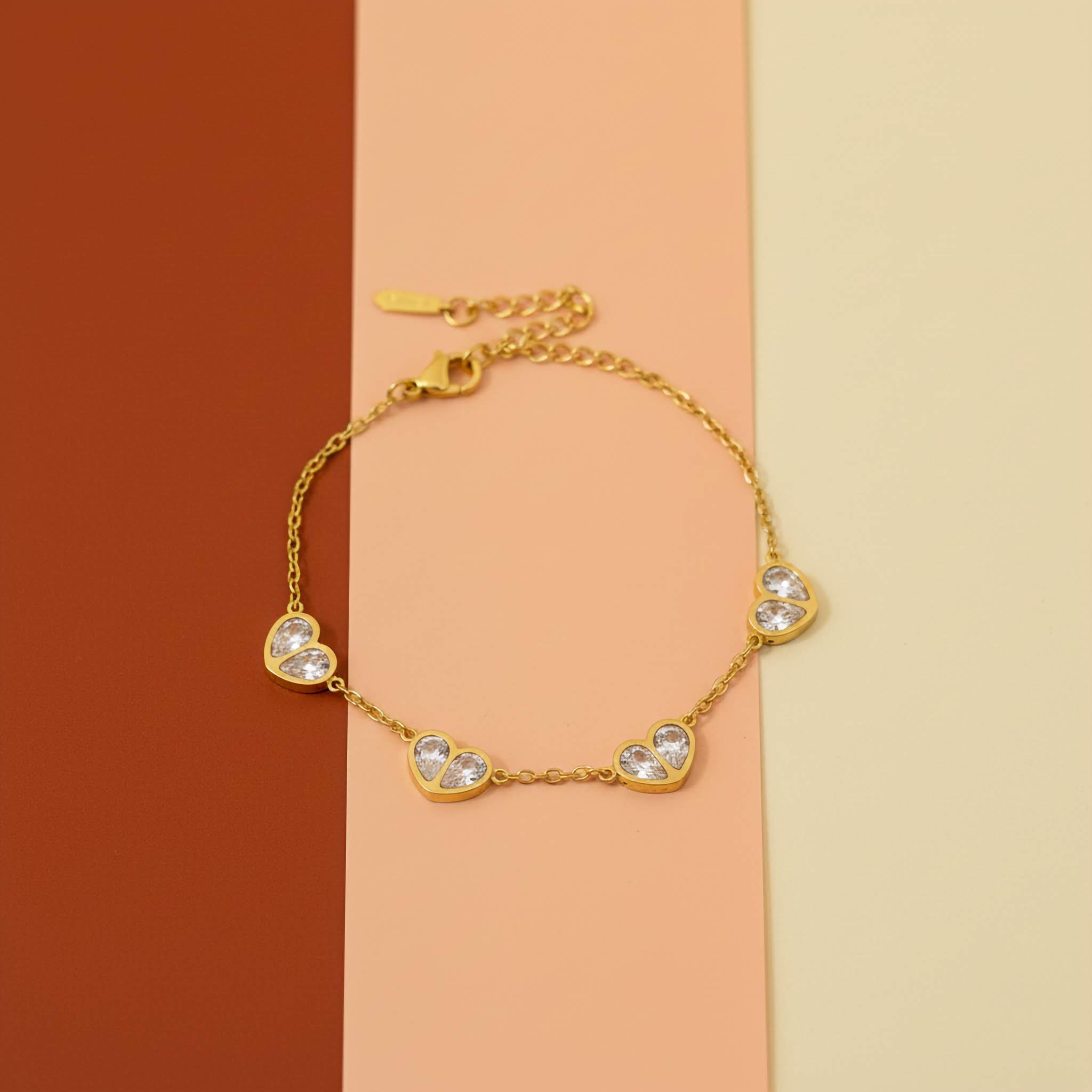 Gold bracelet with heart-shaped charms on a two-tone background