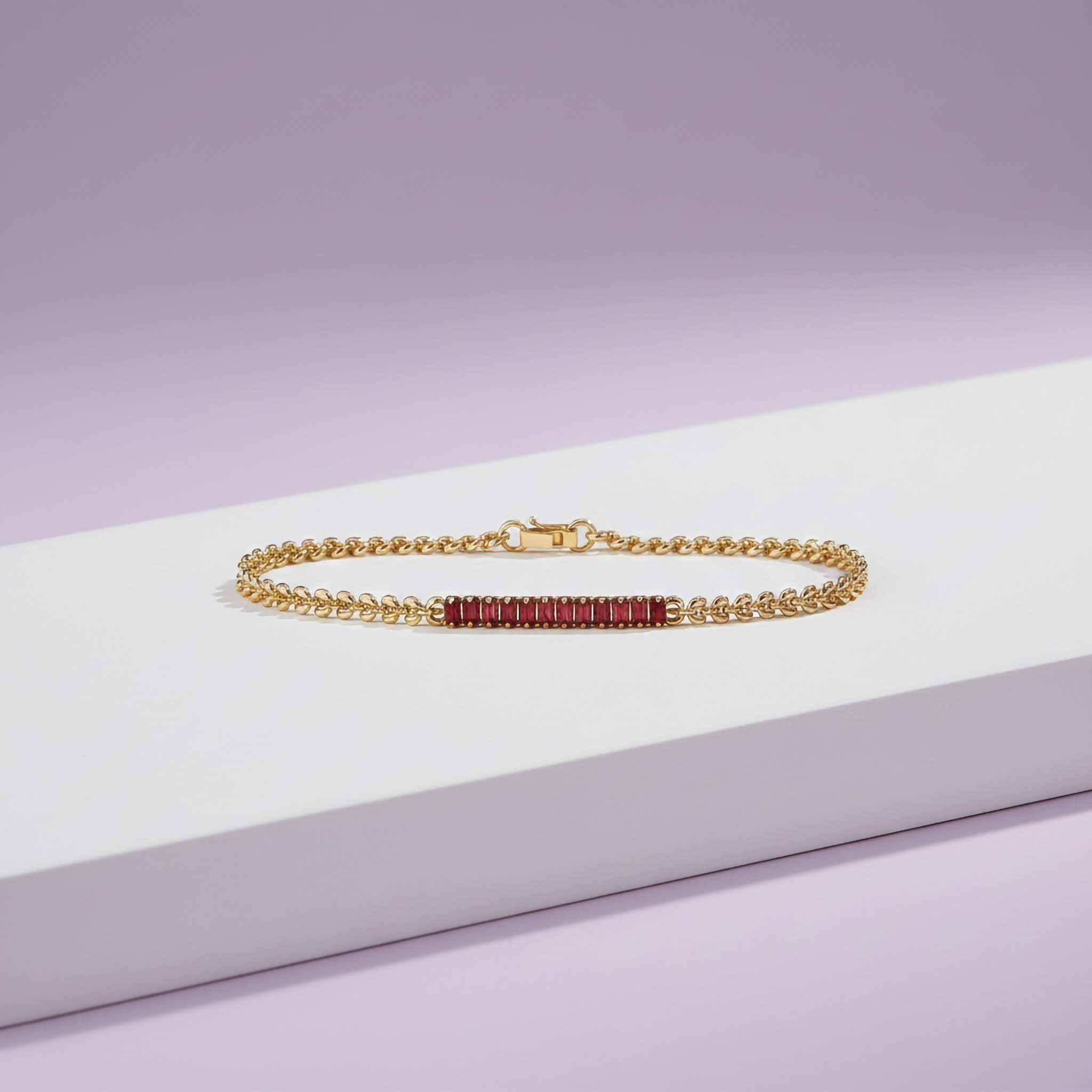 Gold bracelet with red stones on a white and purple gradient background