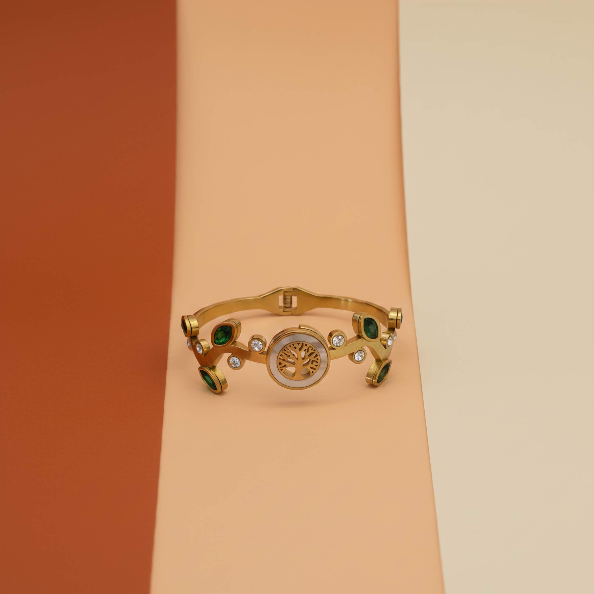 Gold bracelet with tree inspired design on a gradient background