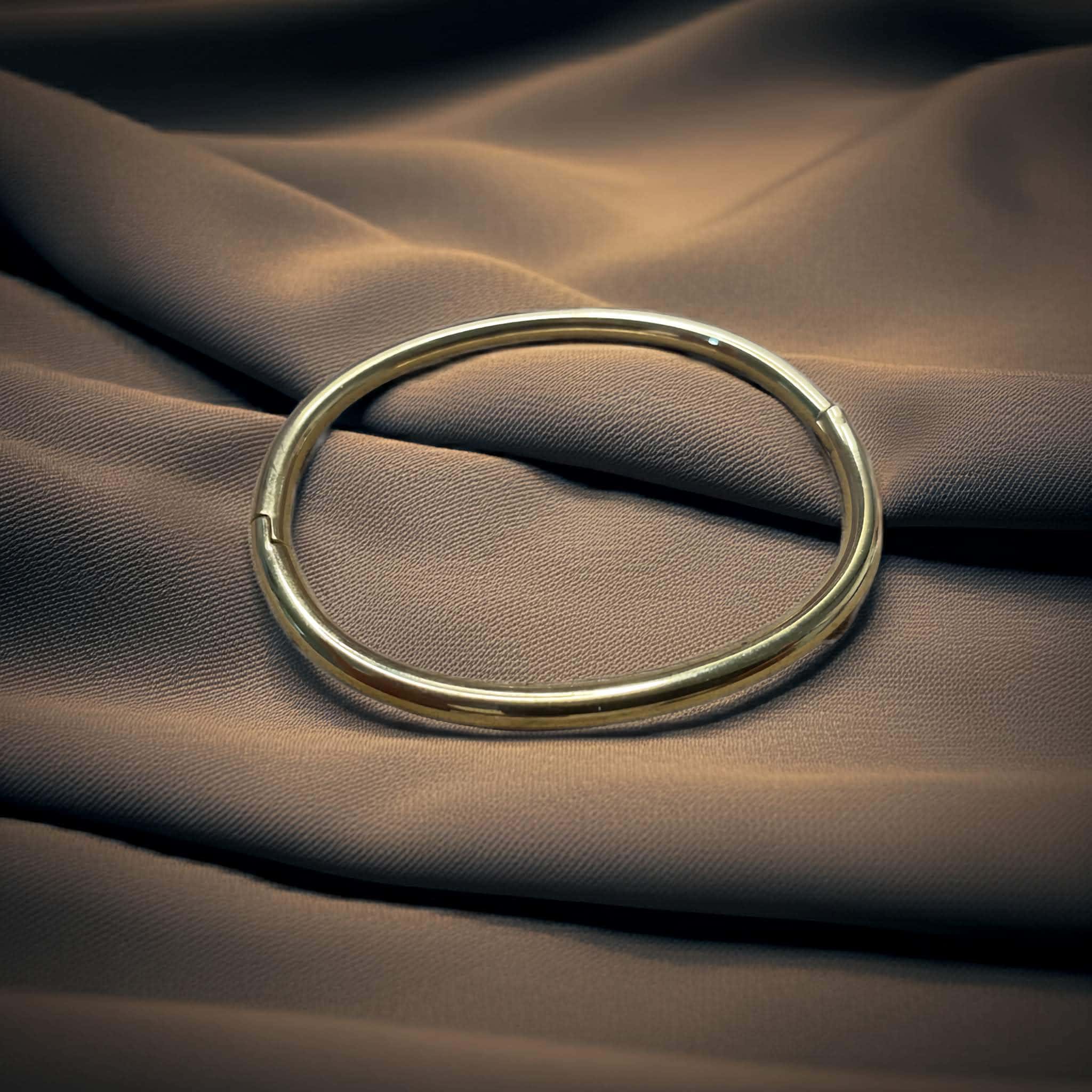 Gold pipe style bracelet on a textured brown fabric surface