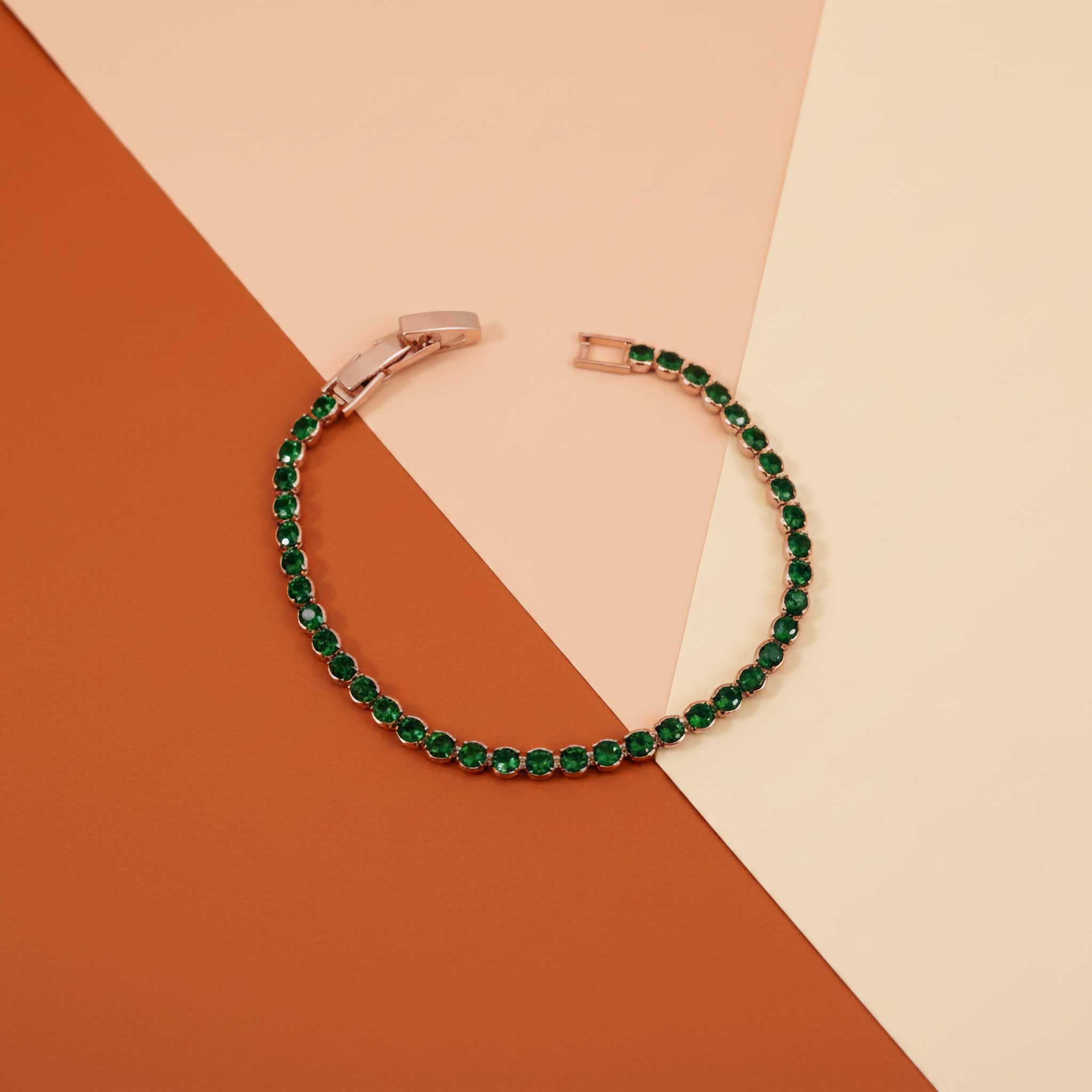Green bracelet with rose gold clasp on a two-tone background