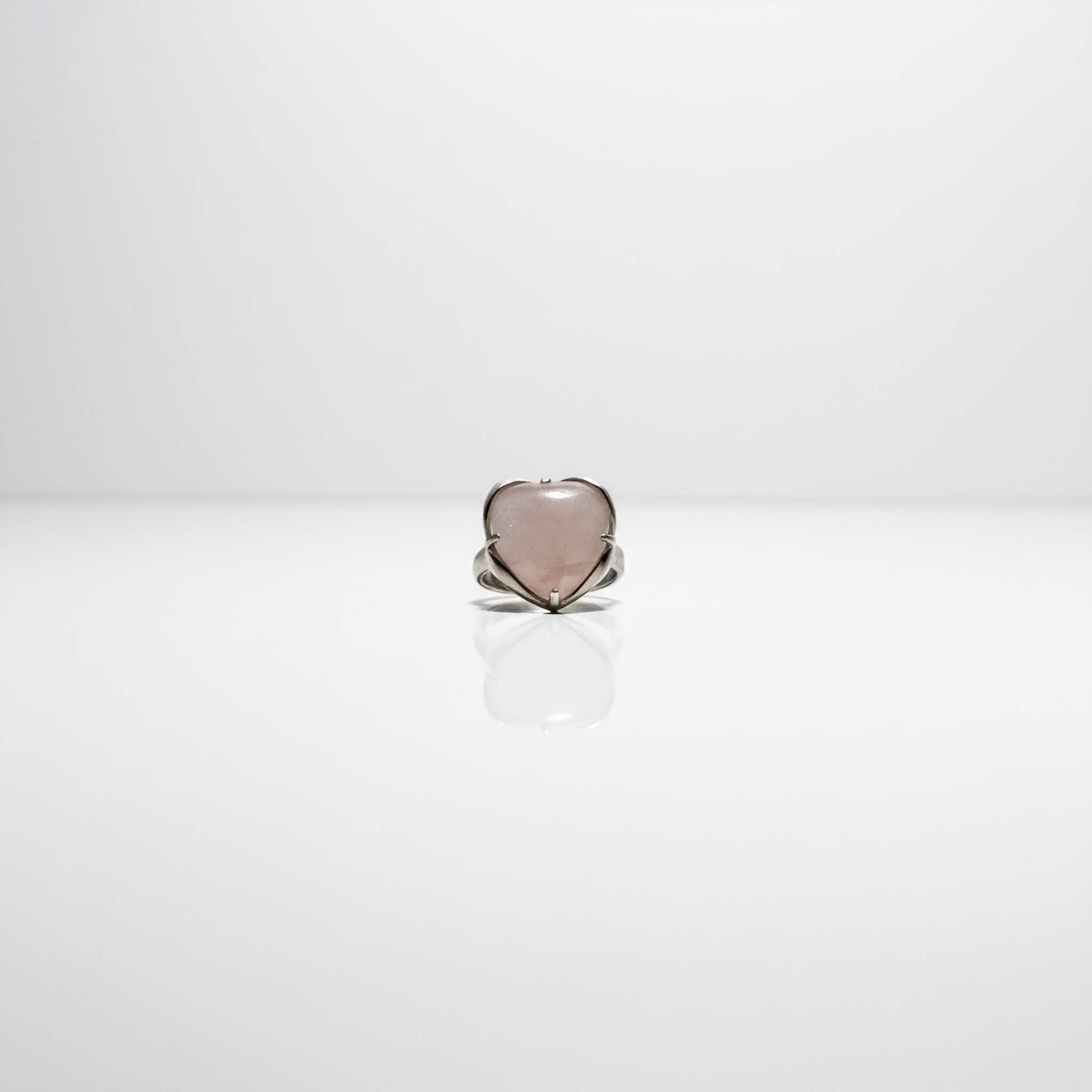 Heart-shaped ring with a light pink stone on a white background