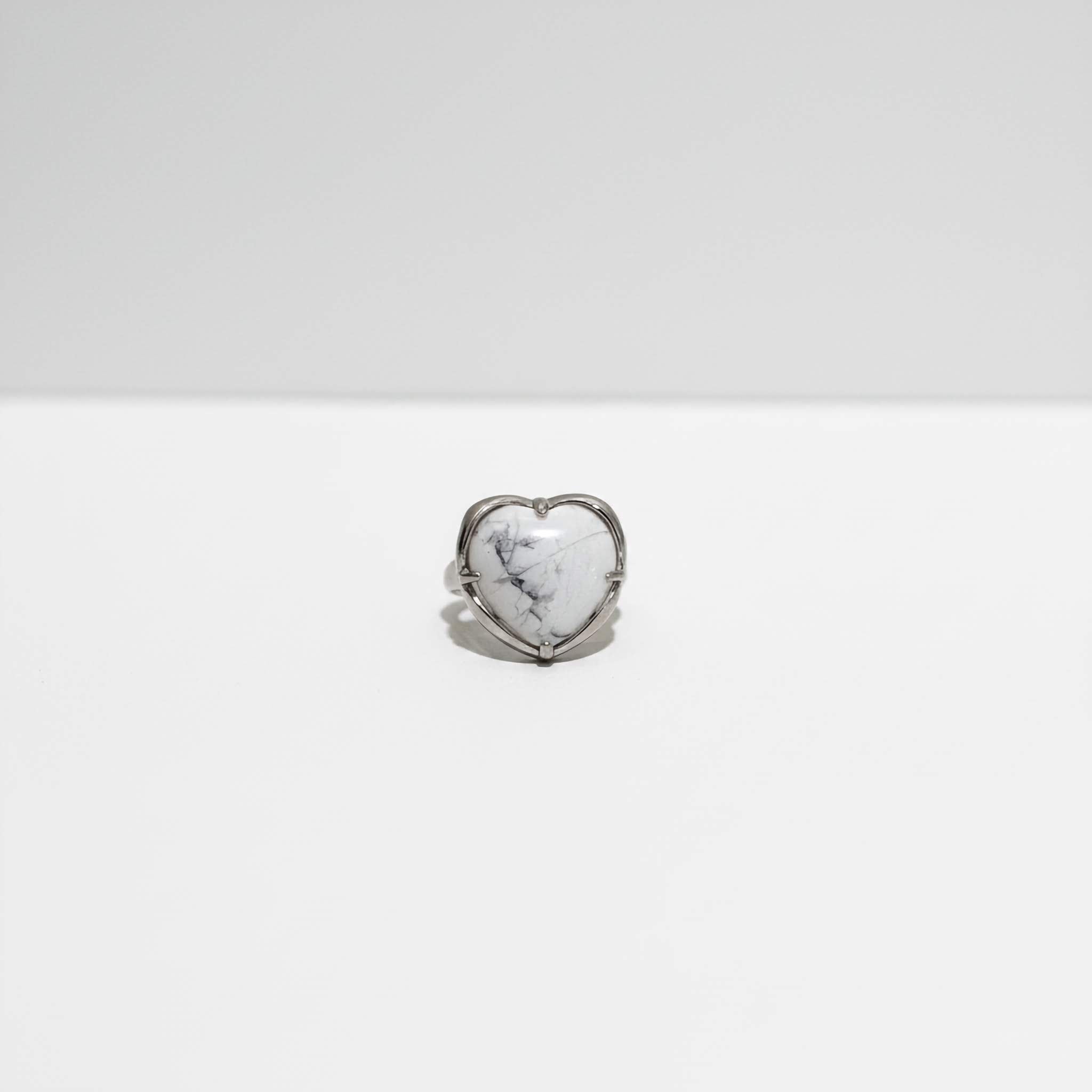 Heart-shaped ring with a white stone on a white background