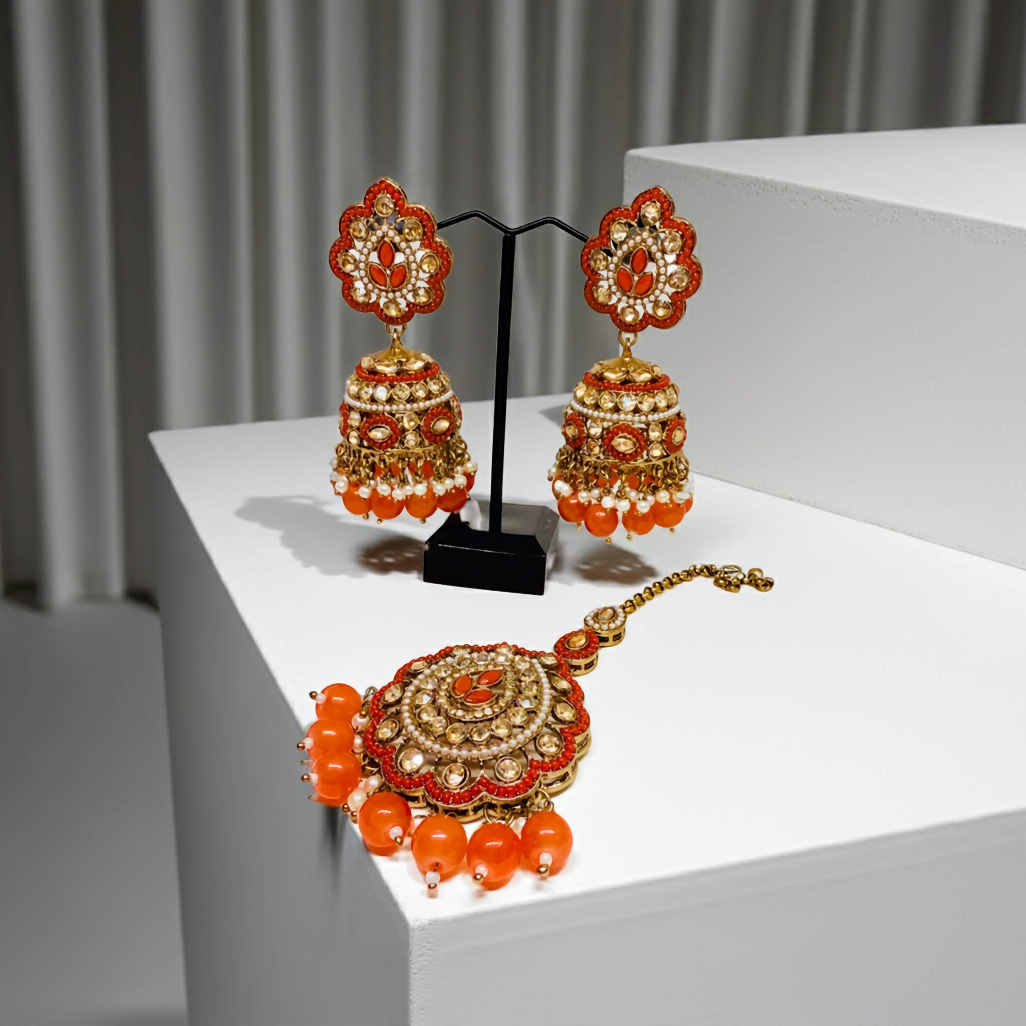 Ornate gold and red mirror jewelry set on a white platform with a neutral background
