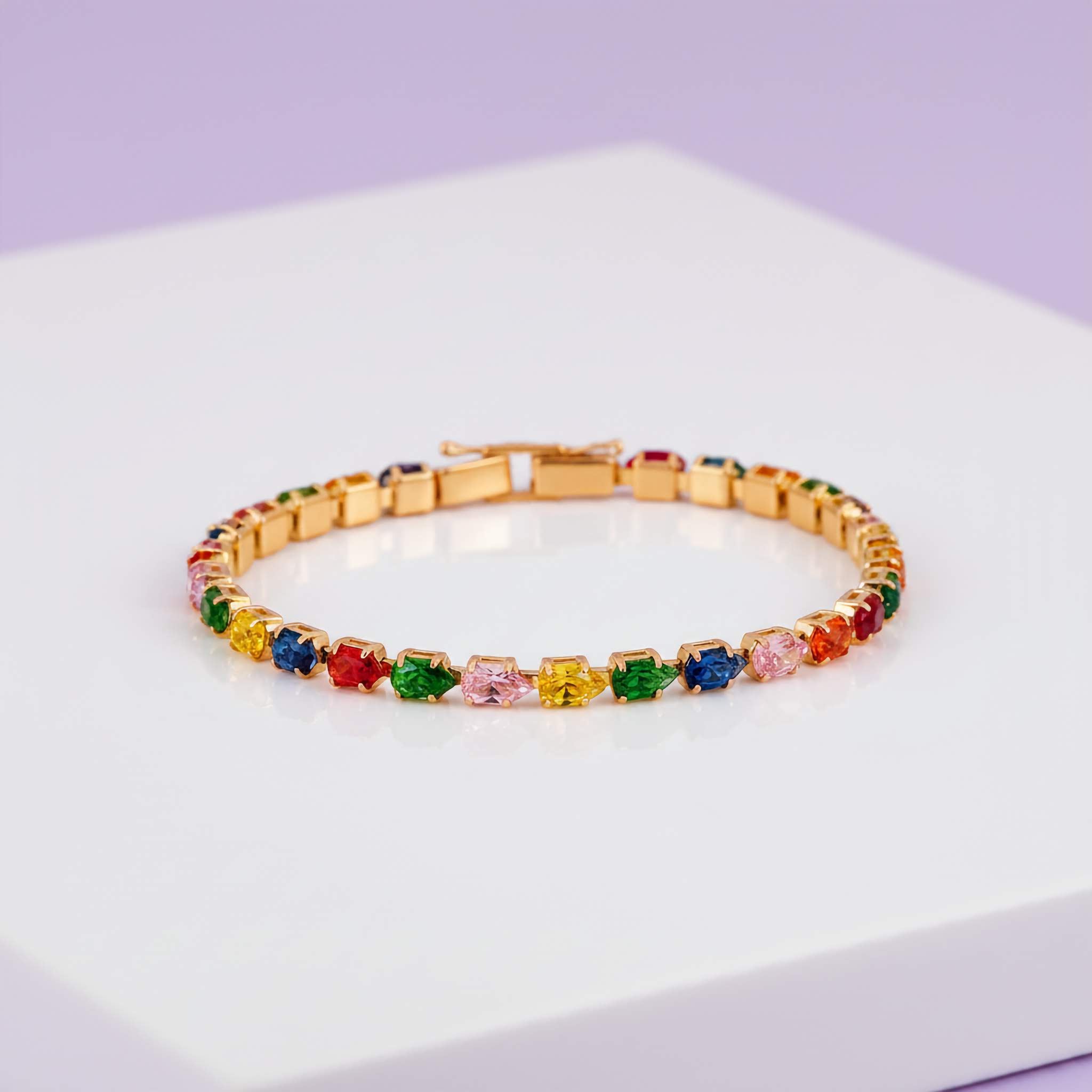 Multicolored gemstone tennis bracelet on a white surface with a light purple background