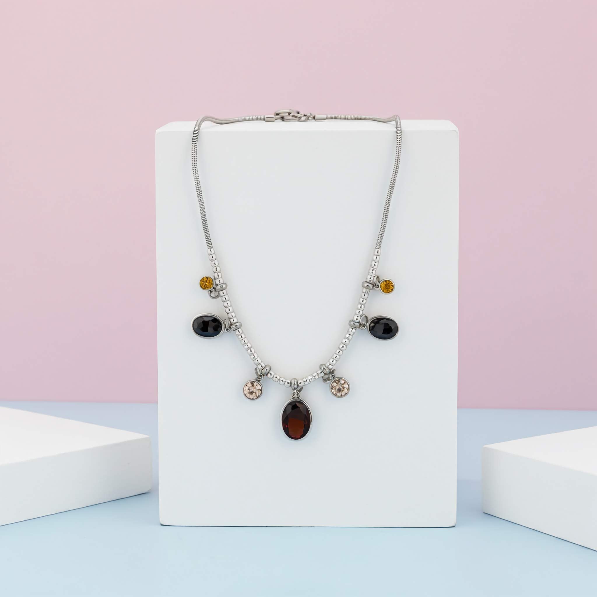 A Under $10 Silver plated Necklace with multicoloured beads on a white box against a pink and blue gradient background