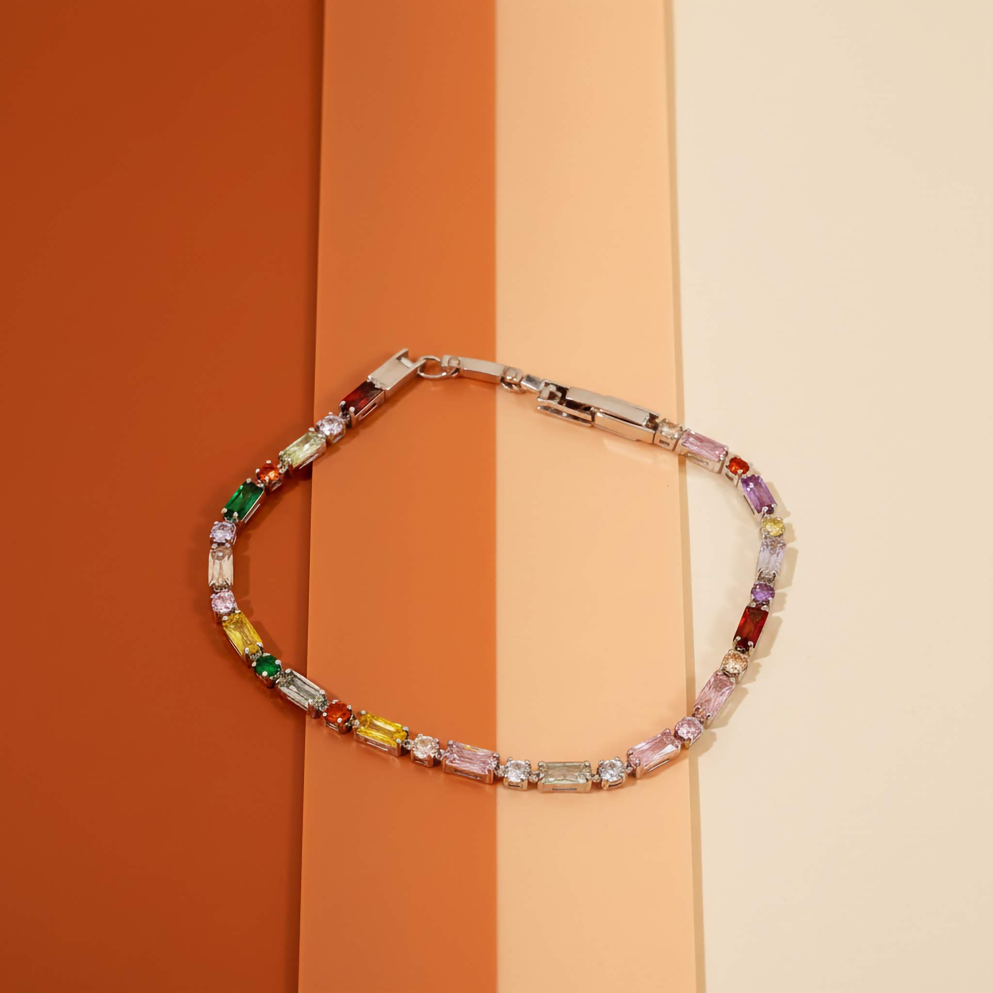 Multicolored silver plated gemstone bracelet on a two-tone orange and beige background