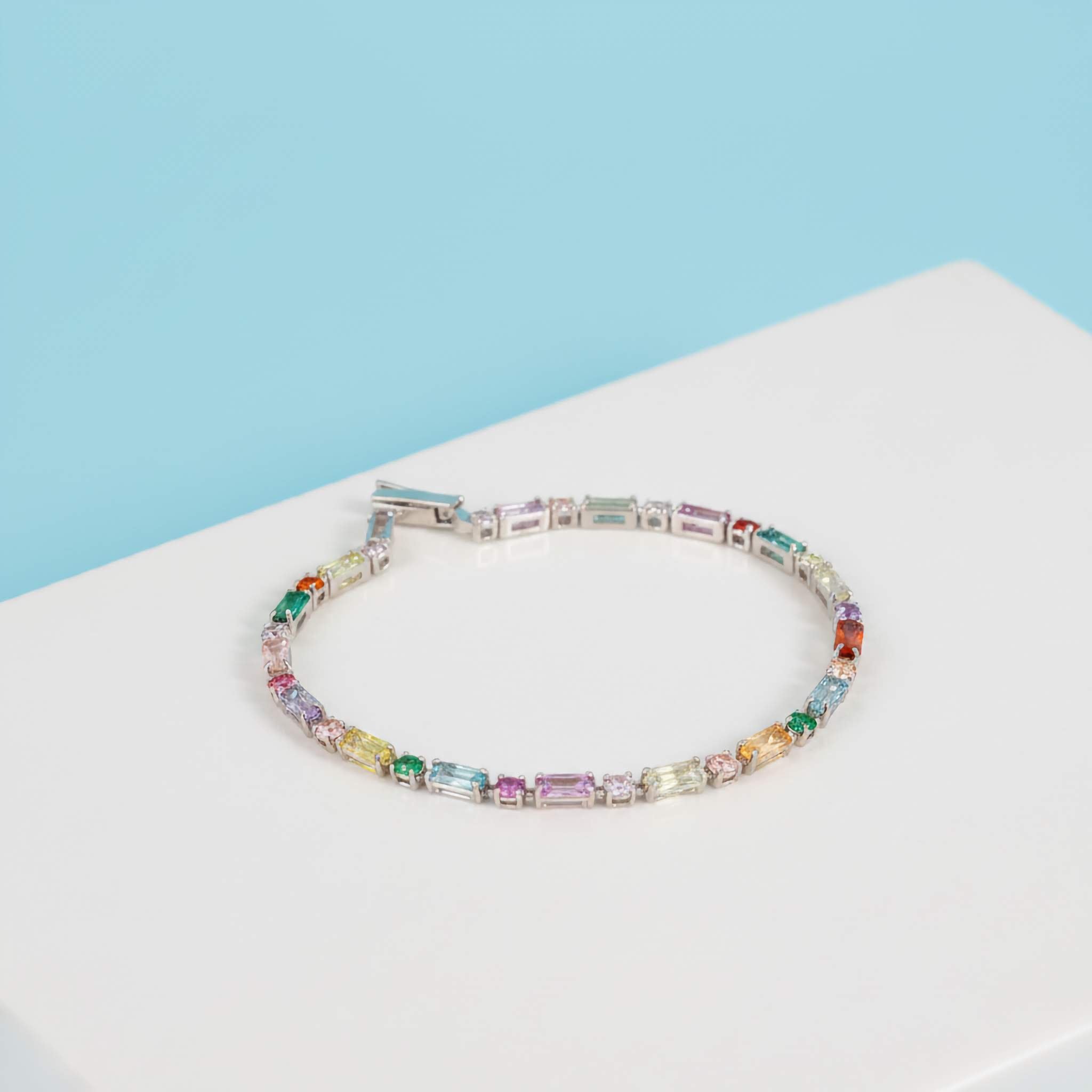 Multicoloured silver plated bracelet on a white surface with a light blue background