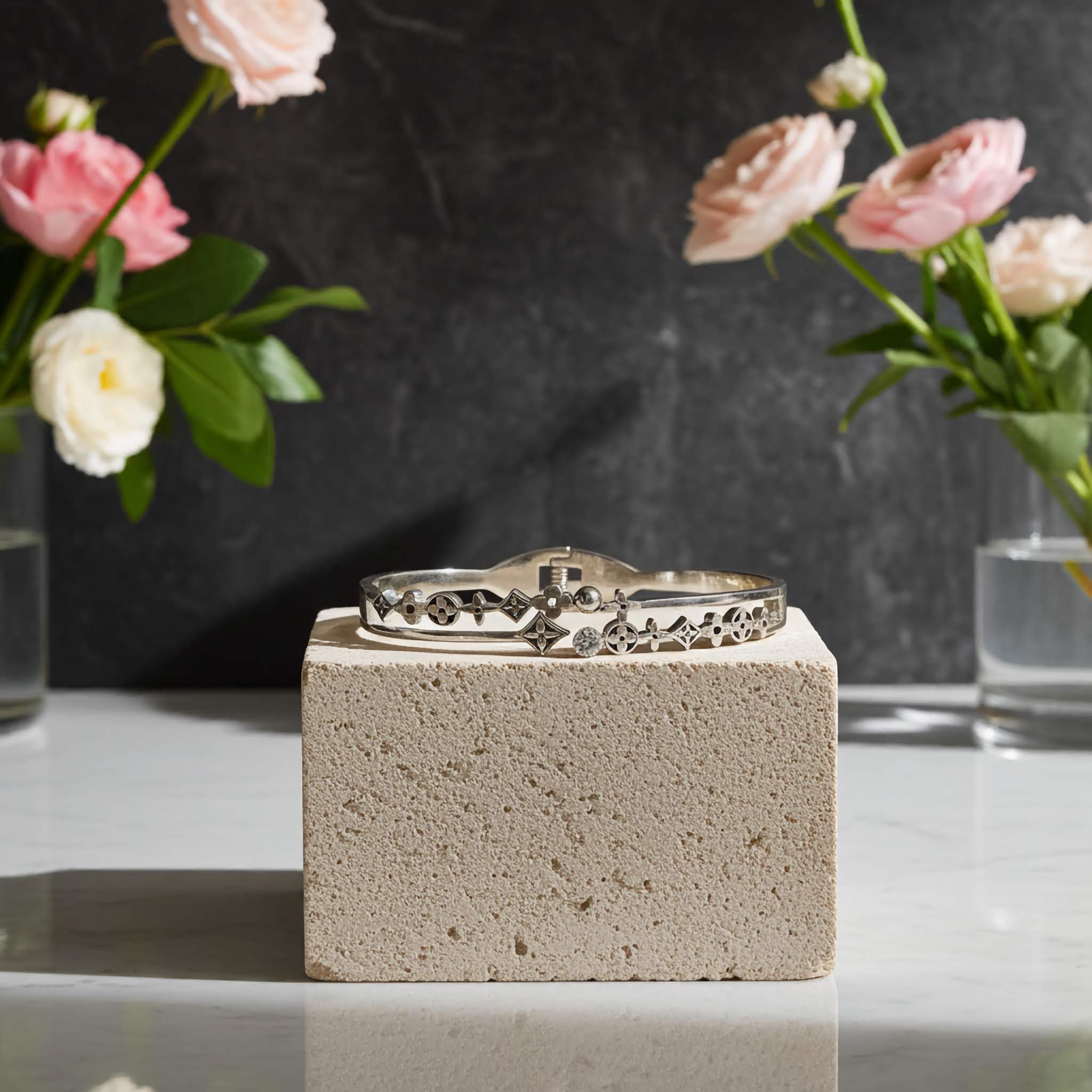 Oxidized Silver bracelet on a concrete block with pink flowers in the background