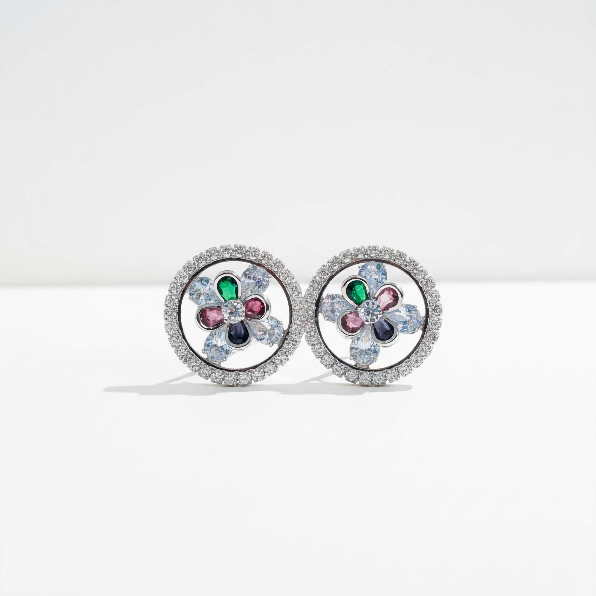 A Pair of earrings studs with floral design and multi-colour gemstones on a white background