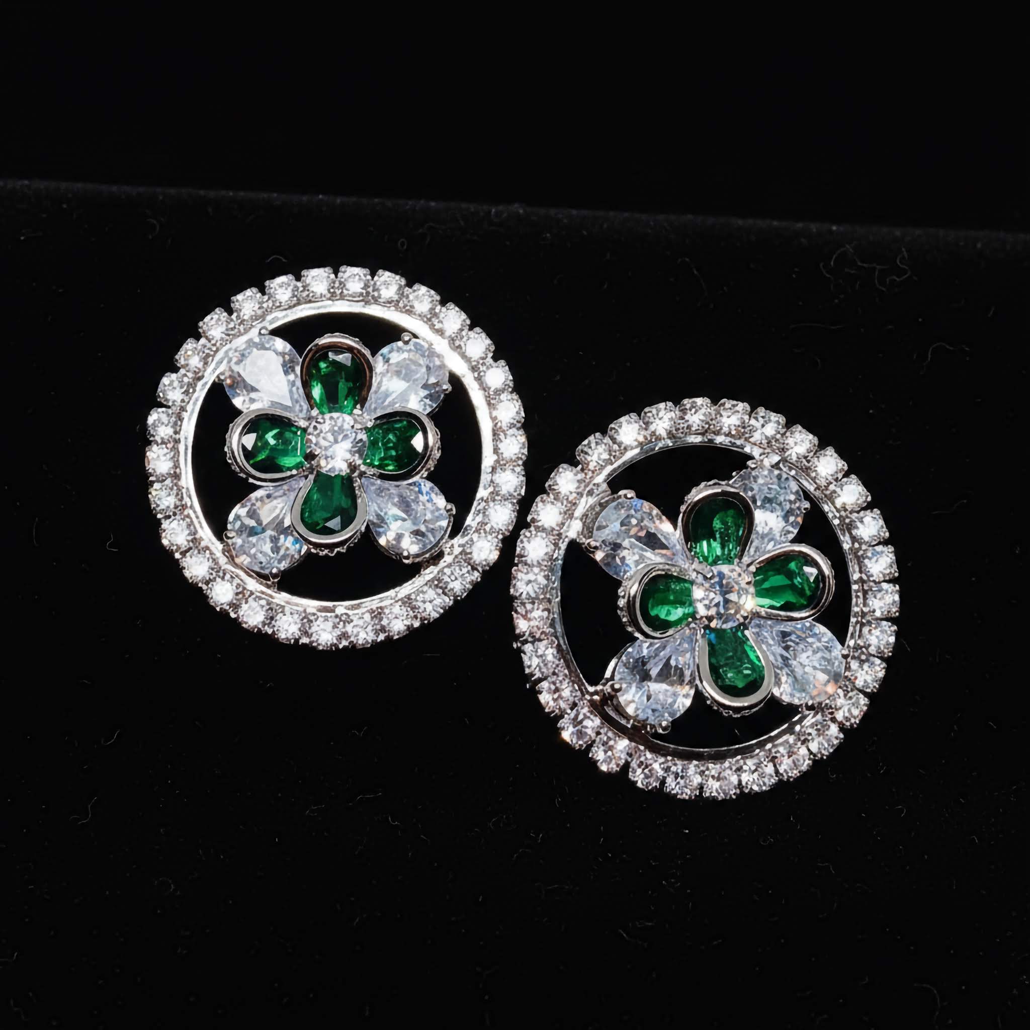 A Pair of round studs with green gemstones and clear stones on a black background