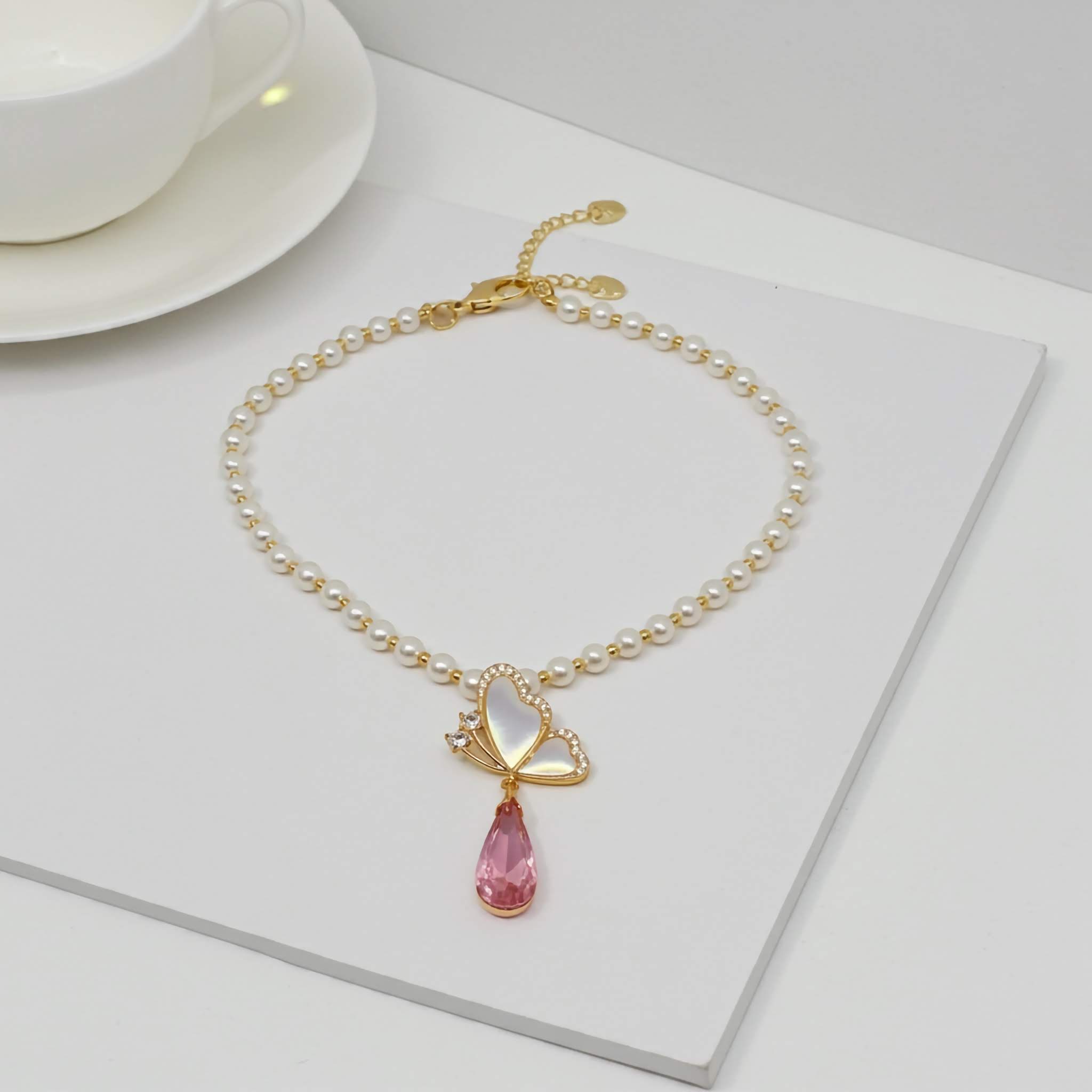 Pearl Necklace with a pink teardrop pendant on a white surface