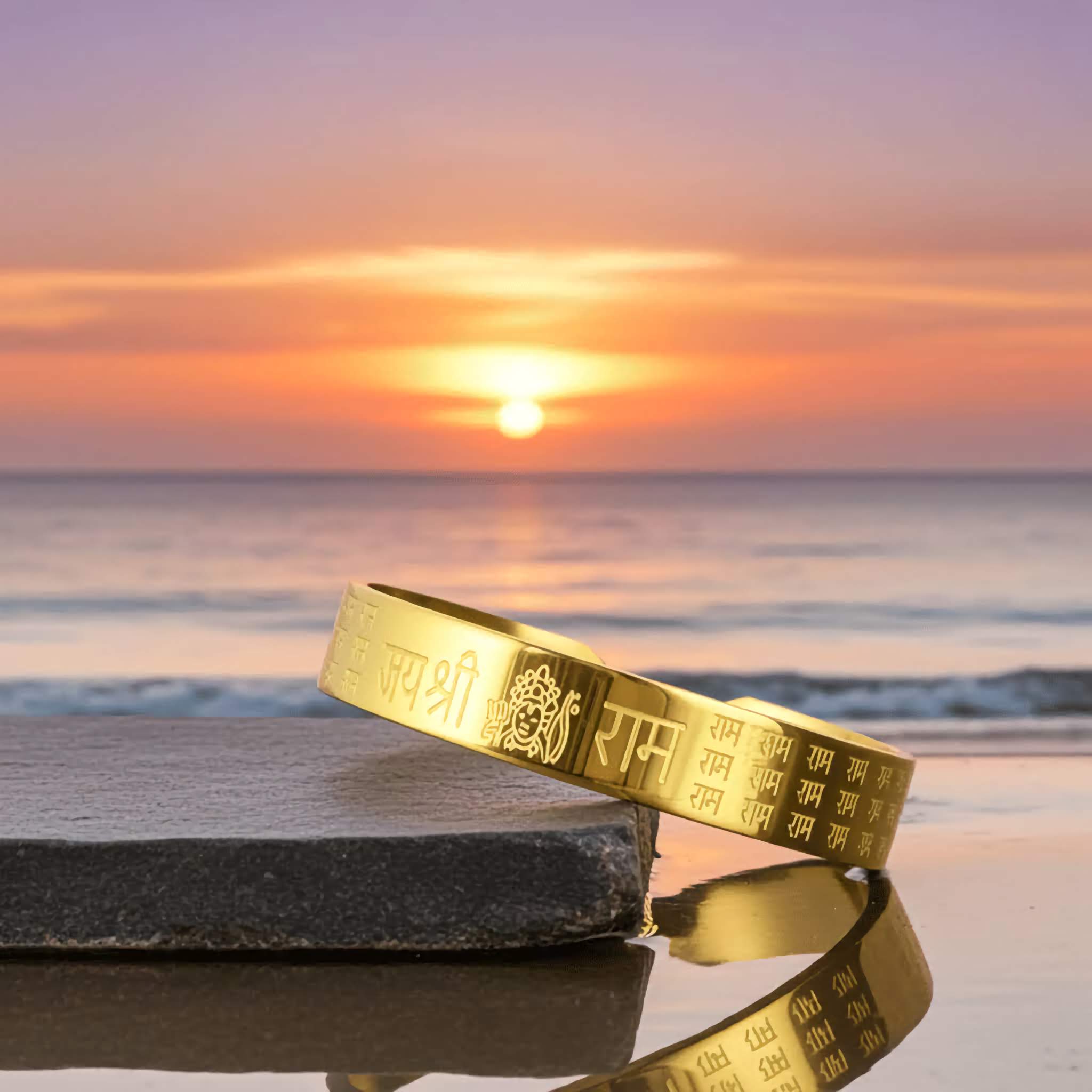 A Gold bracelet with engraved Ram text on a rock at sunset by the sea