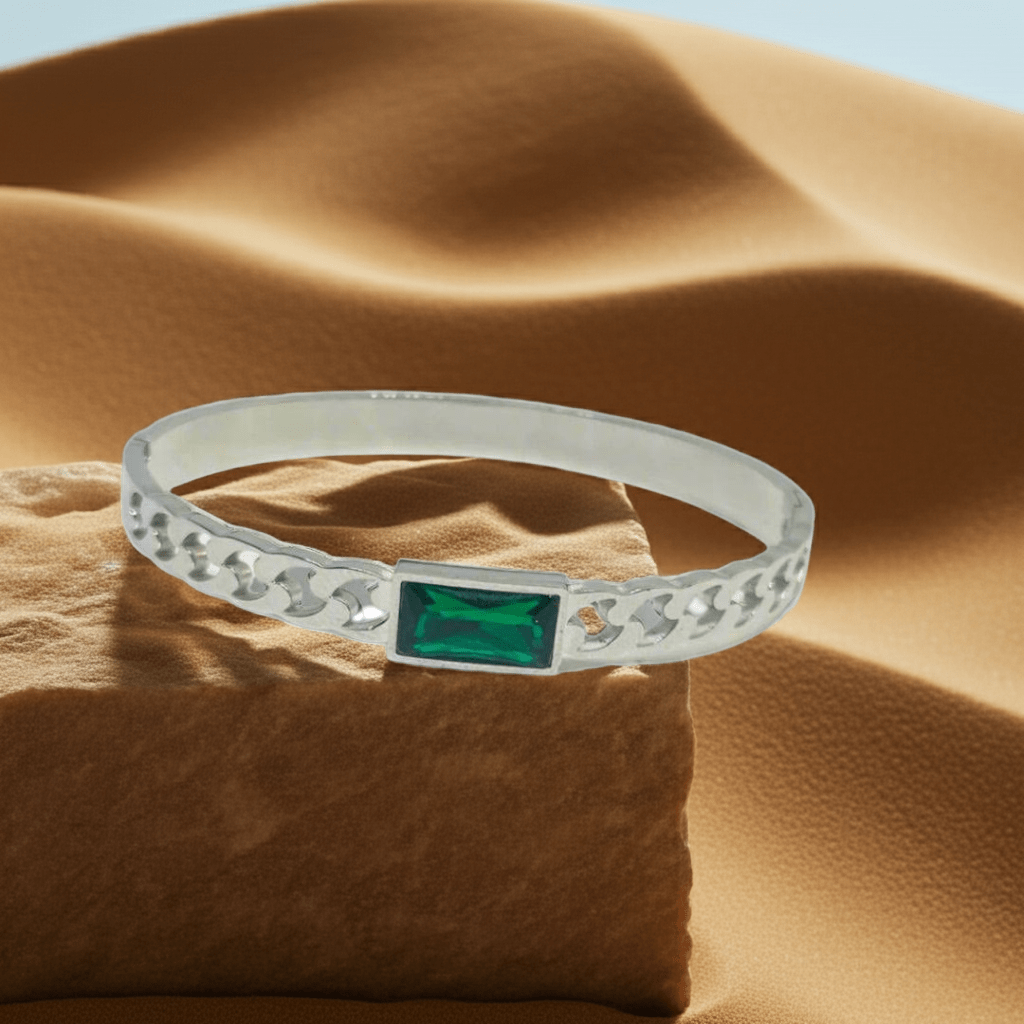 Silver ring with a green gemstone on a textured brown surface