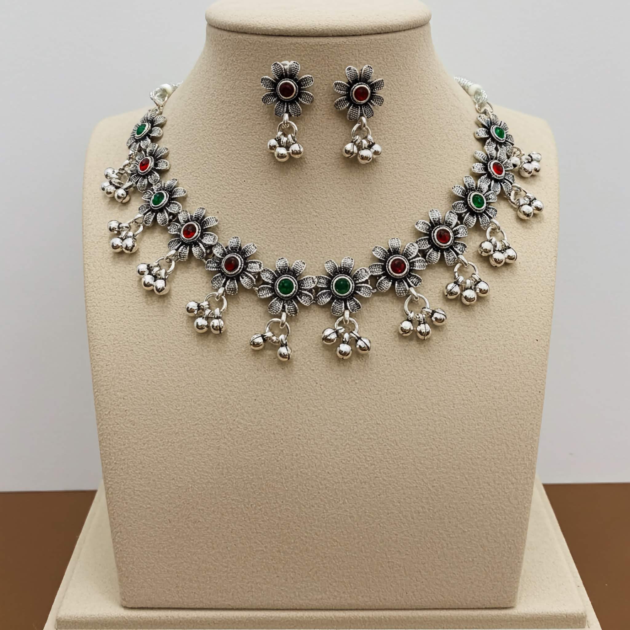Silver floral necklace and earrings set on a mannequin bust.