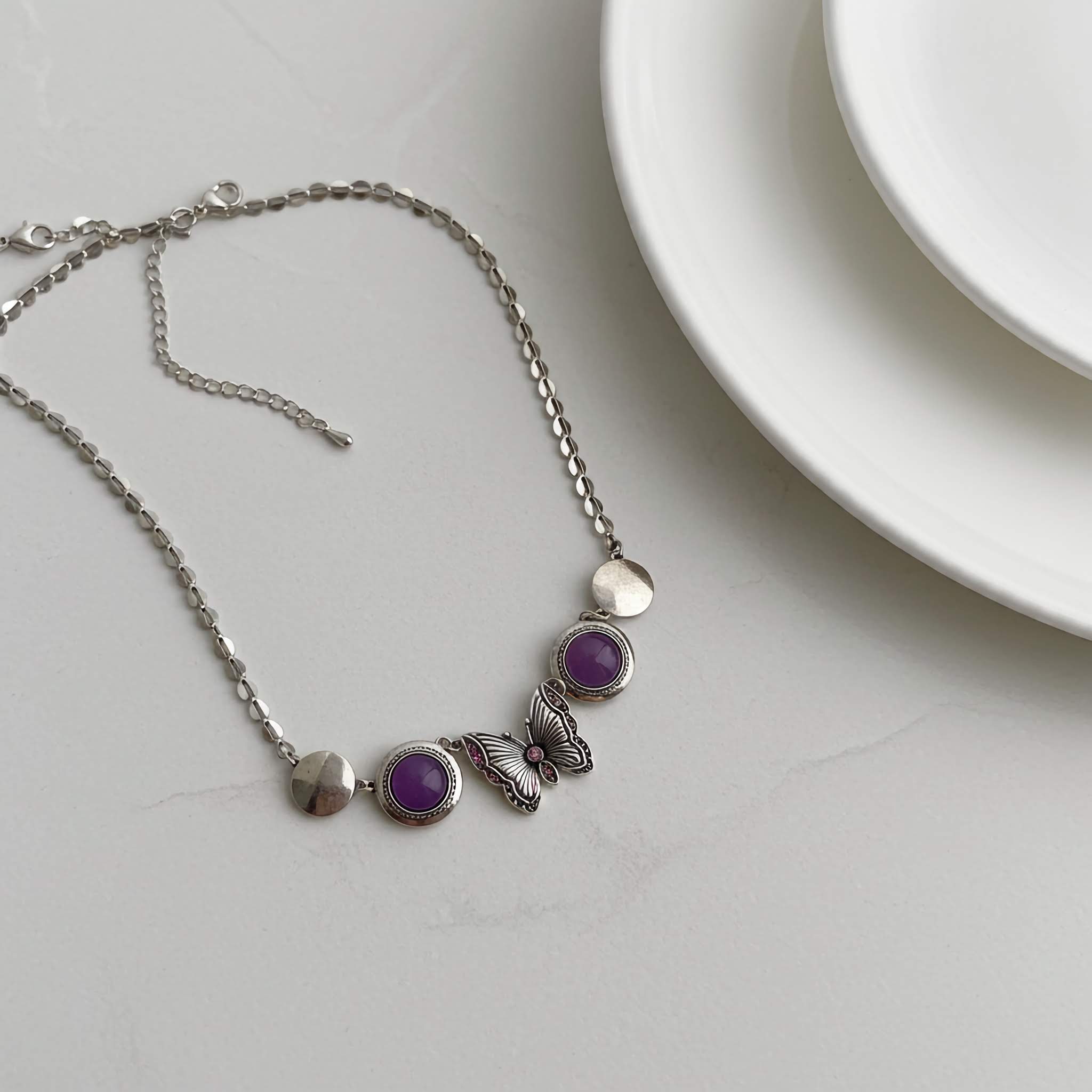 German silver under $10 Necklace with purple beads and butterfly charm on a white surface