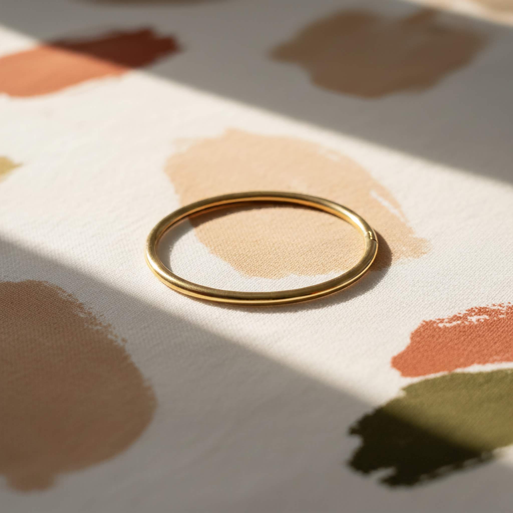 Simple Gold bangle on a surface with abstract brown and beige patterns