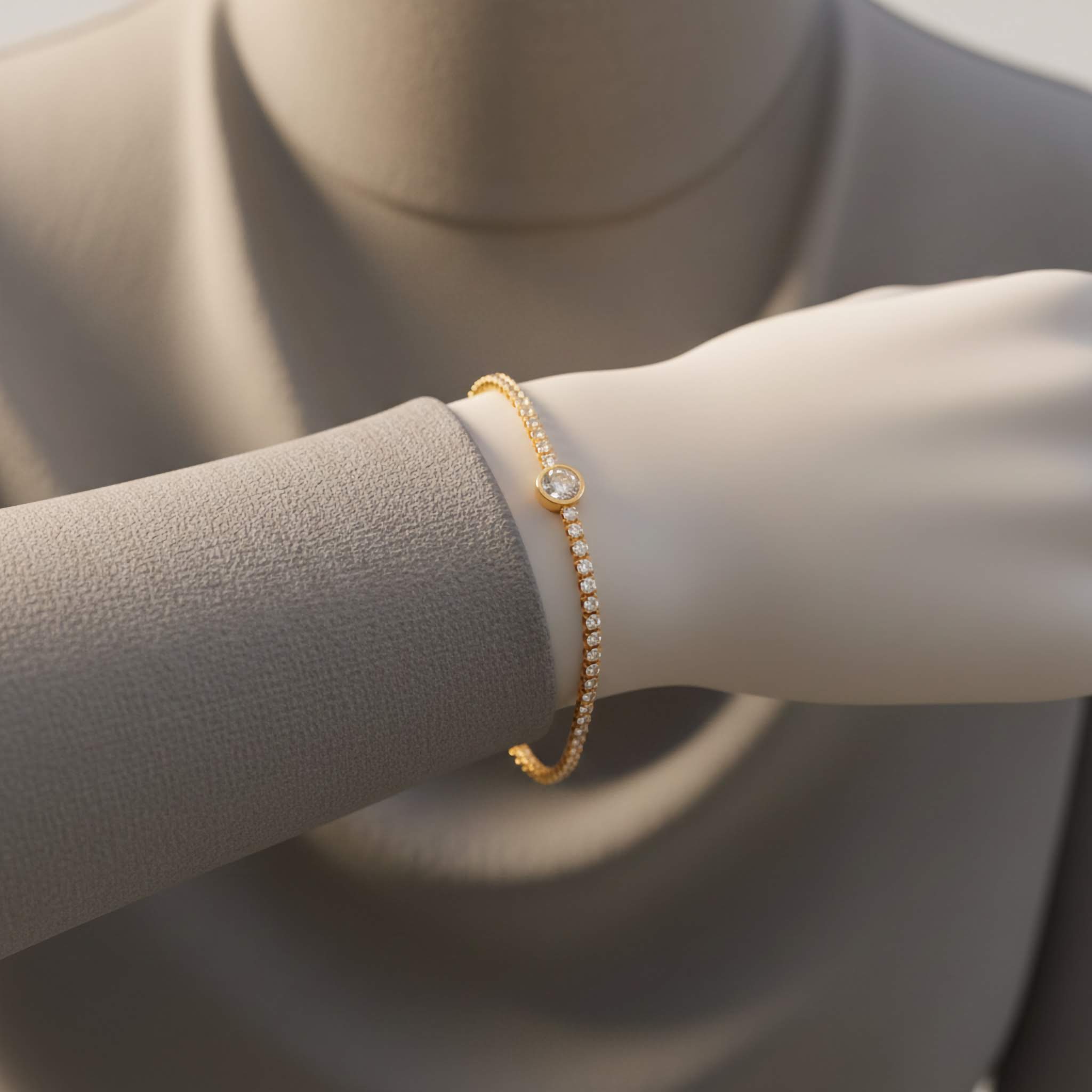 Gold plated tennis bracelet on a mannequin arm with a neutral background