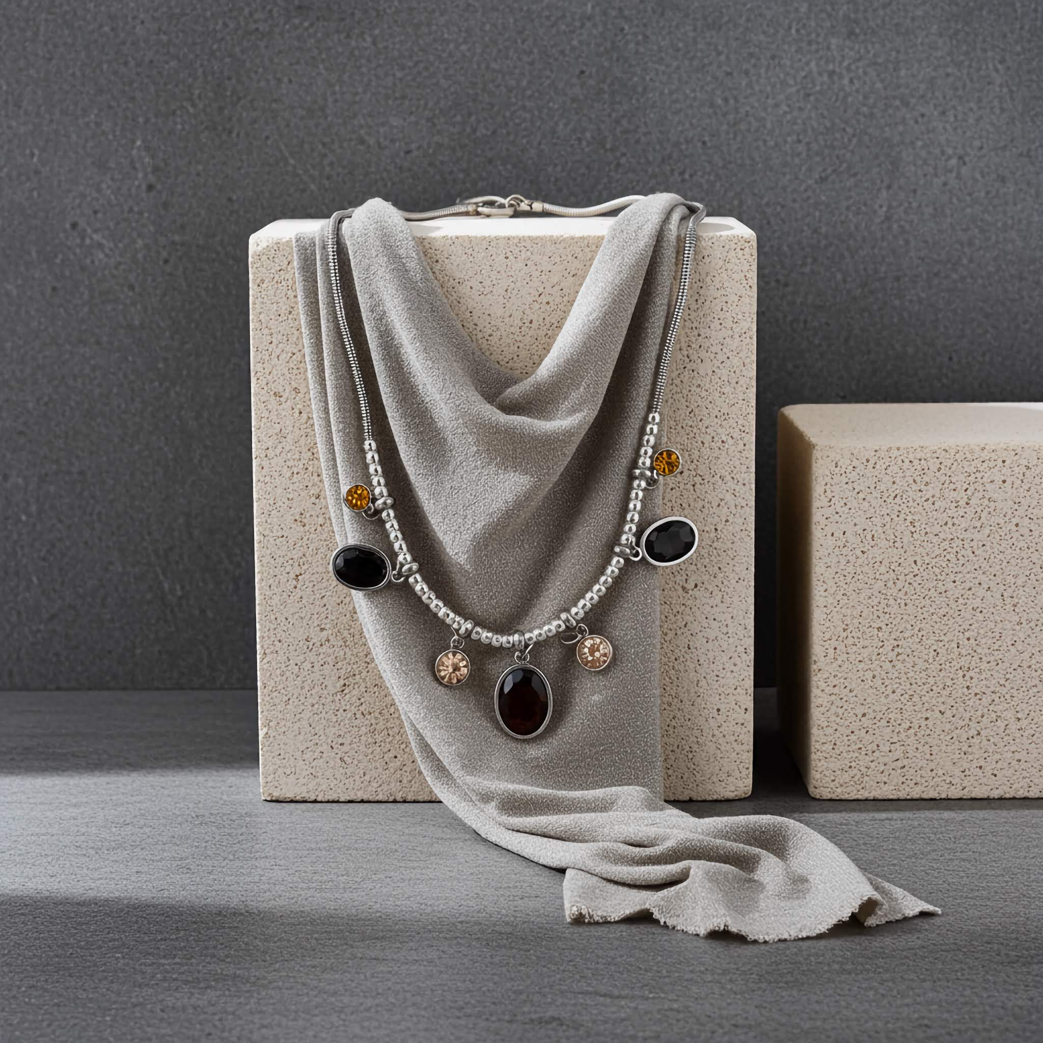 A under $10 silver plated Necklace with colorful pendants draped over a gray fabric on a textured surface.