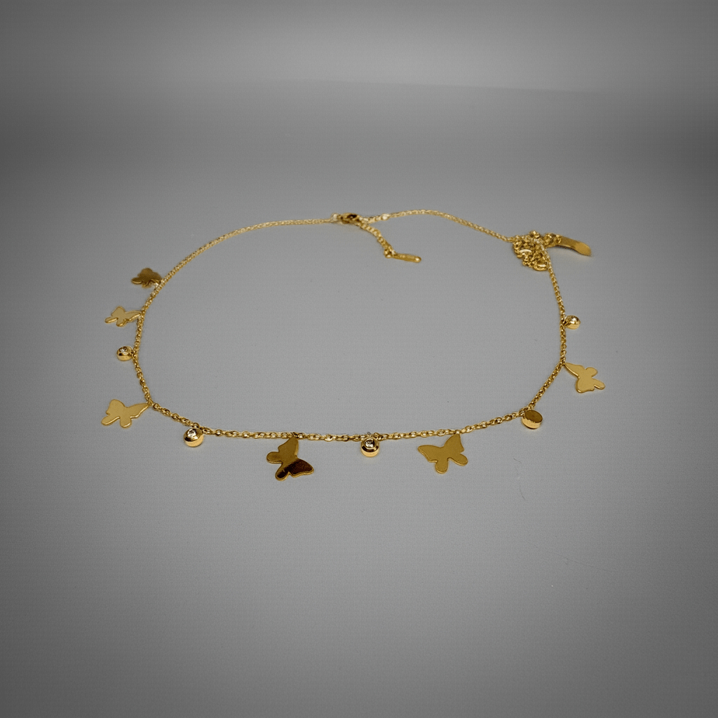 Gold necklace with butterfly charms on a gray background