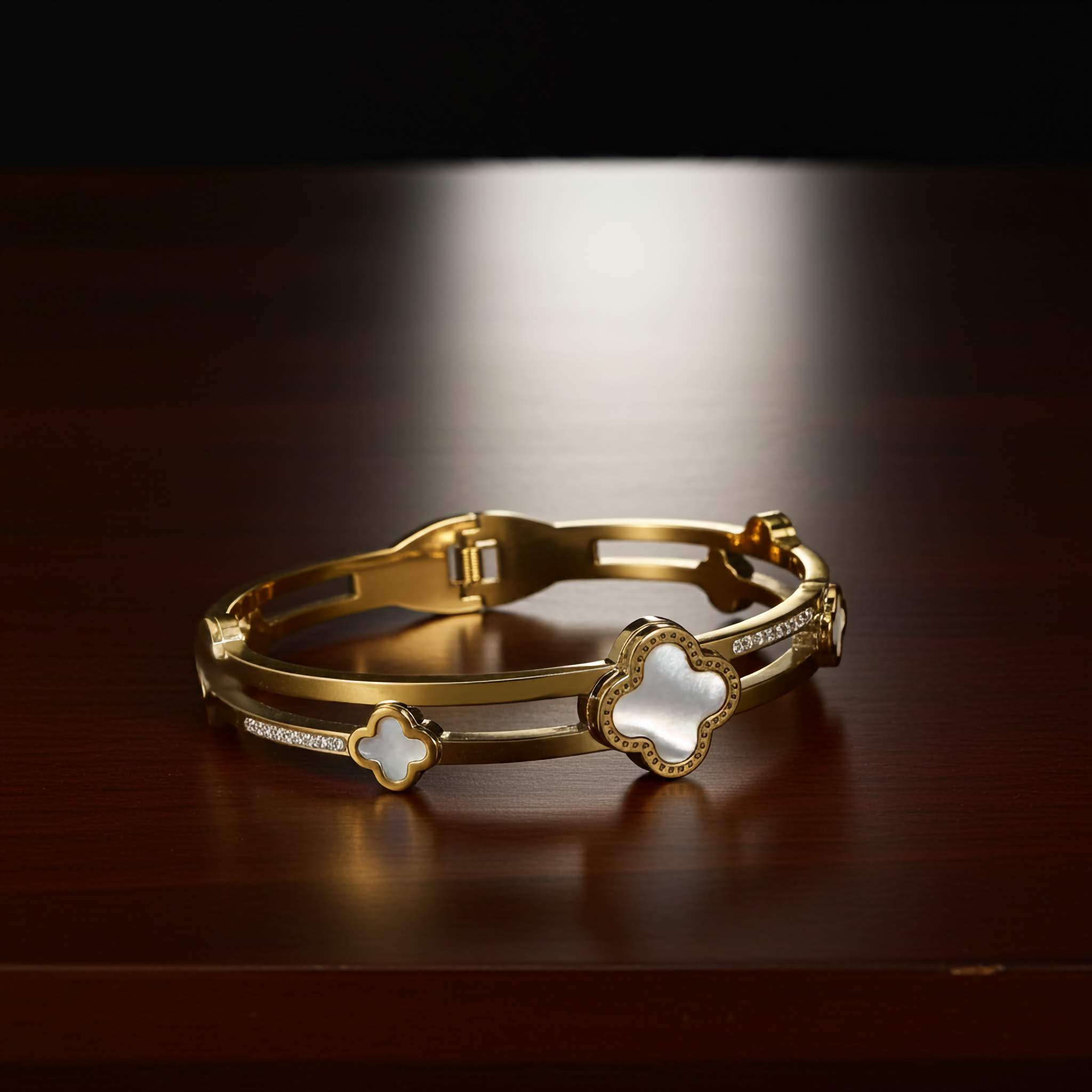 Gold clover bracelet with star-shaped ends on a dark surface
