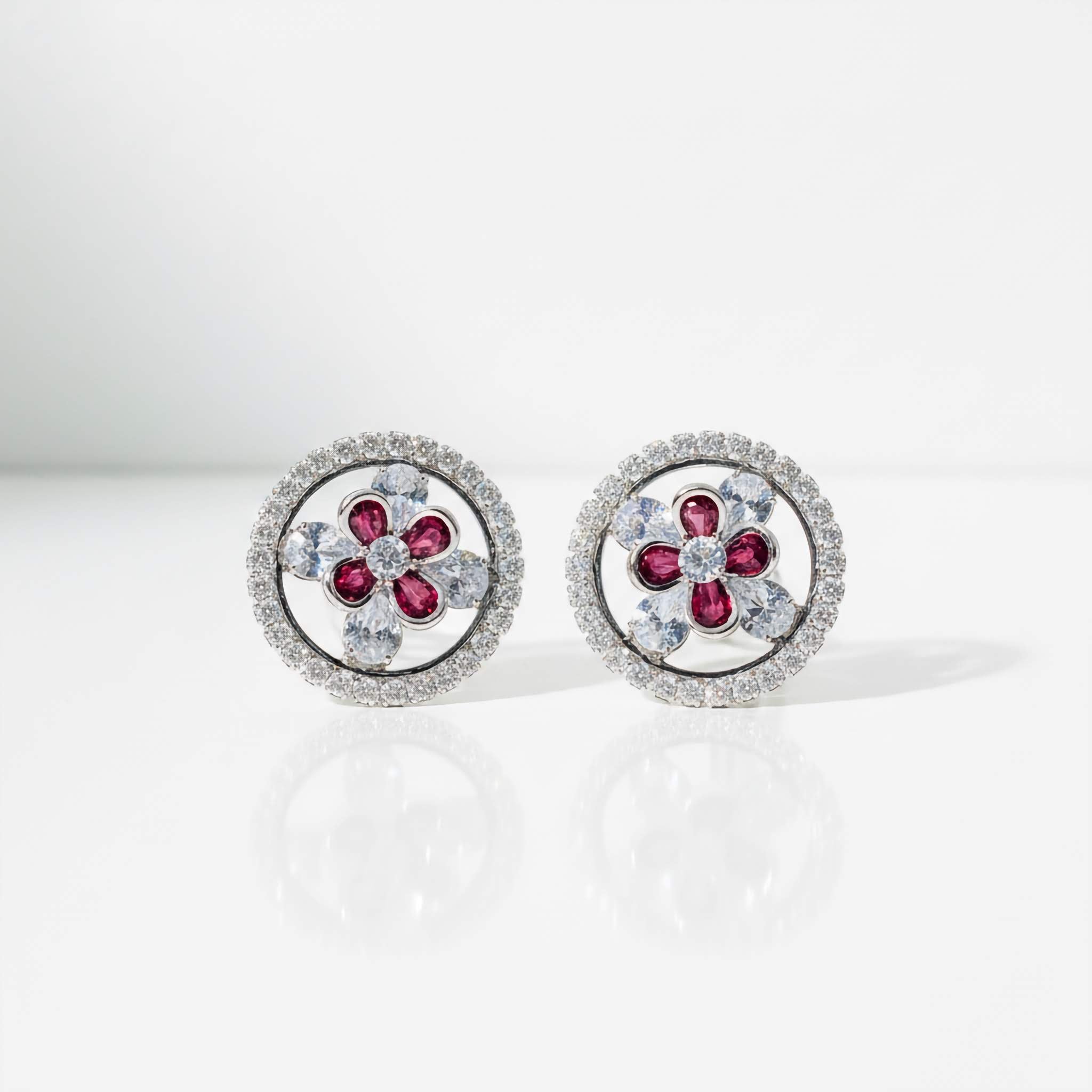 A Pair of Stud earrings with floral design and red gemstones on a white background