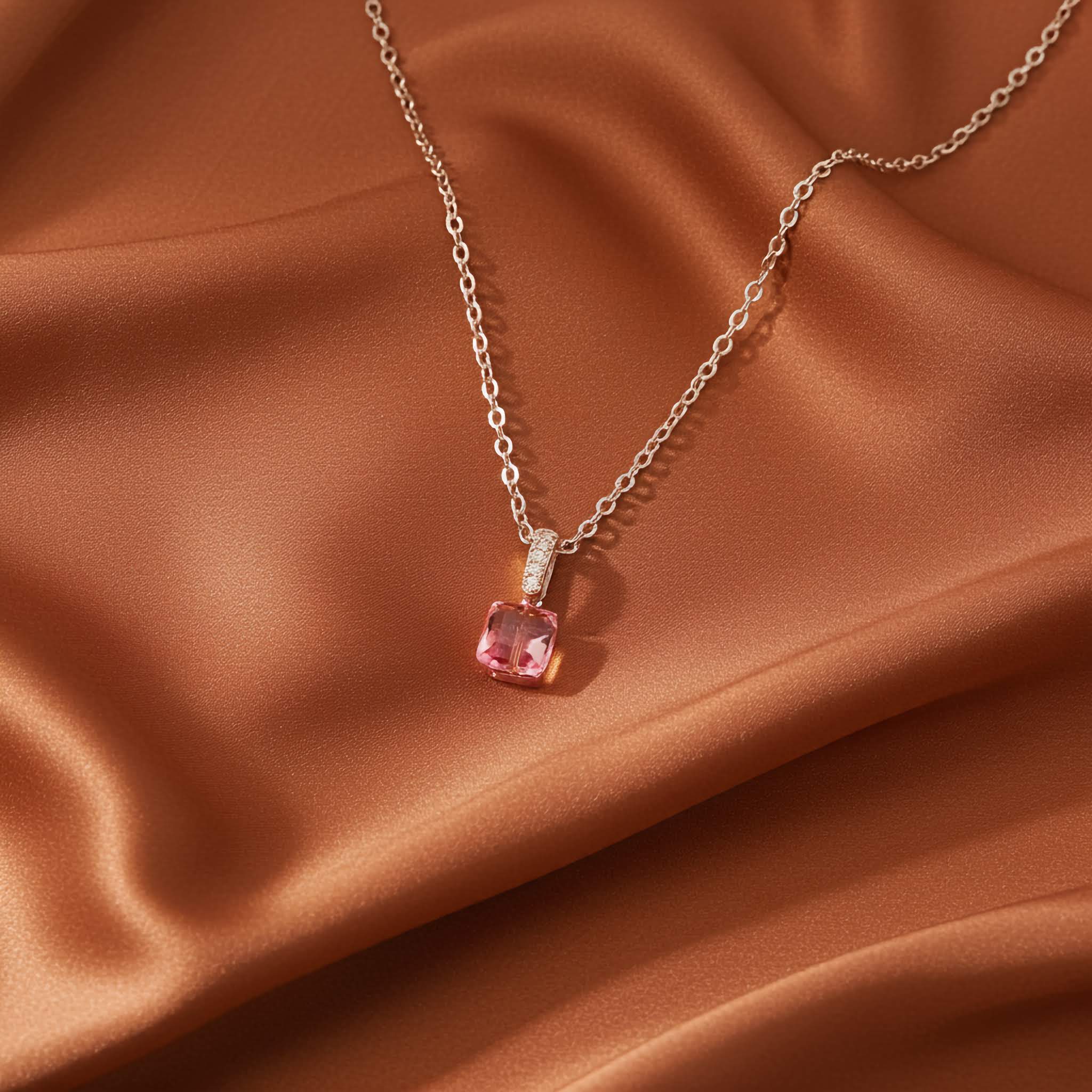 Radiant cut pink pendant Necklace on a brown fabric background