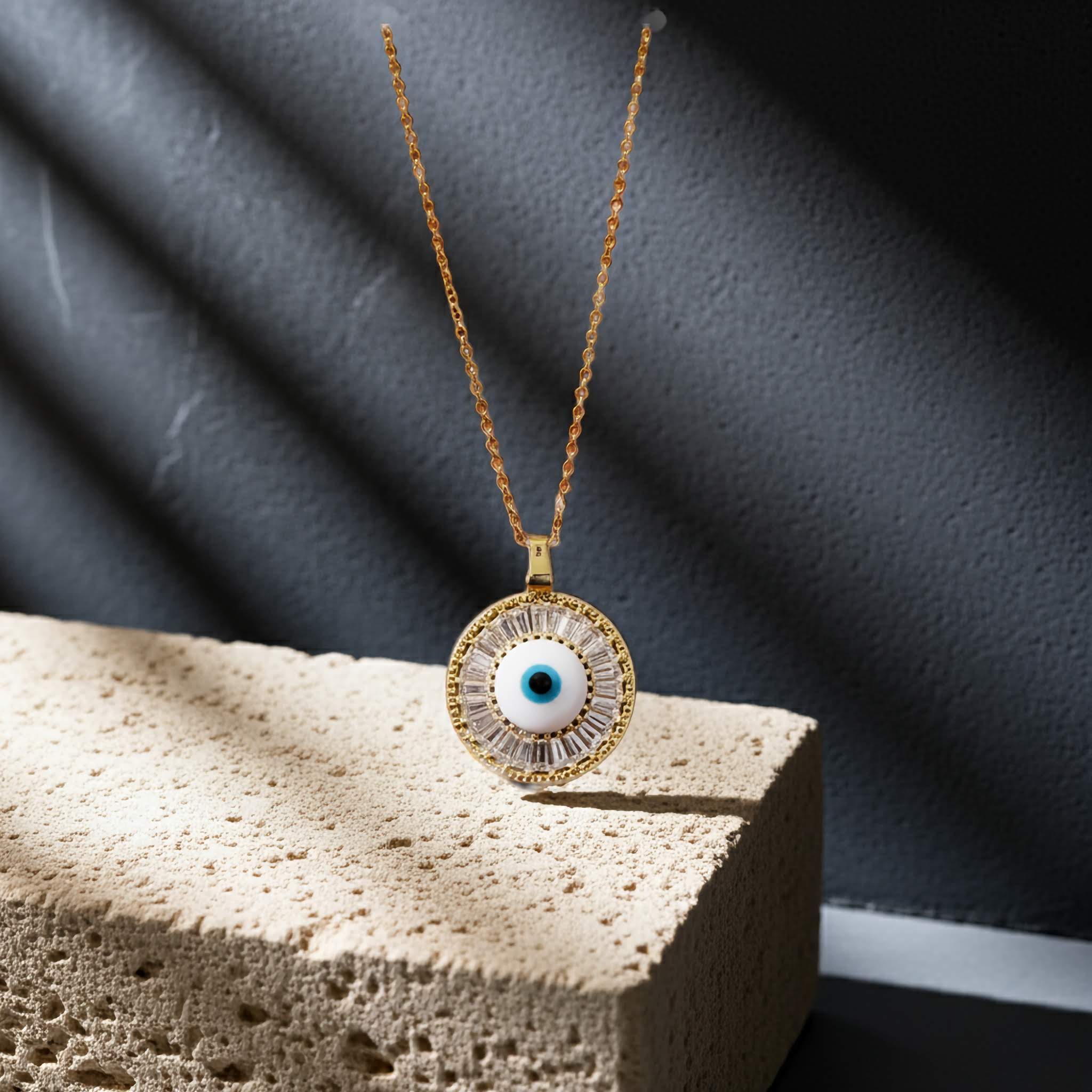 A evil eye design Gold necklace with an eye-shaped pendant on a textured surface