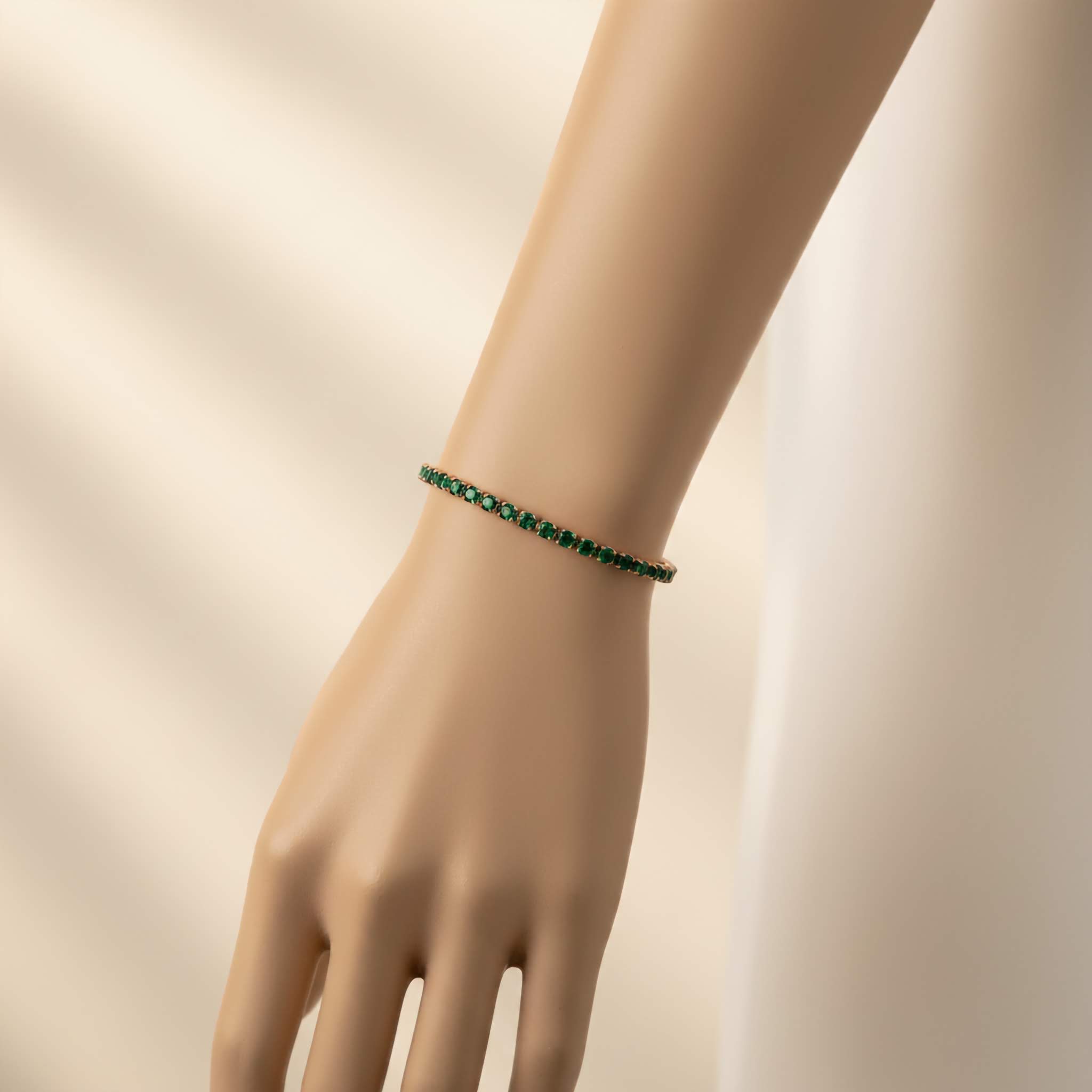 Green beaded tennis bracelet on a wrist against a beige background
