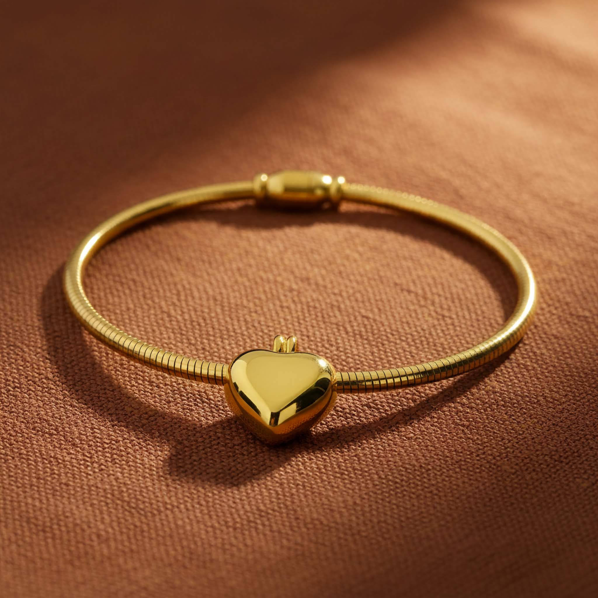 Gold plated bracelet with a heart-shaped clasp on a brown fabric background