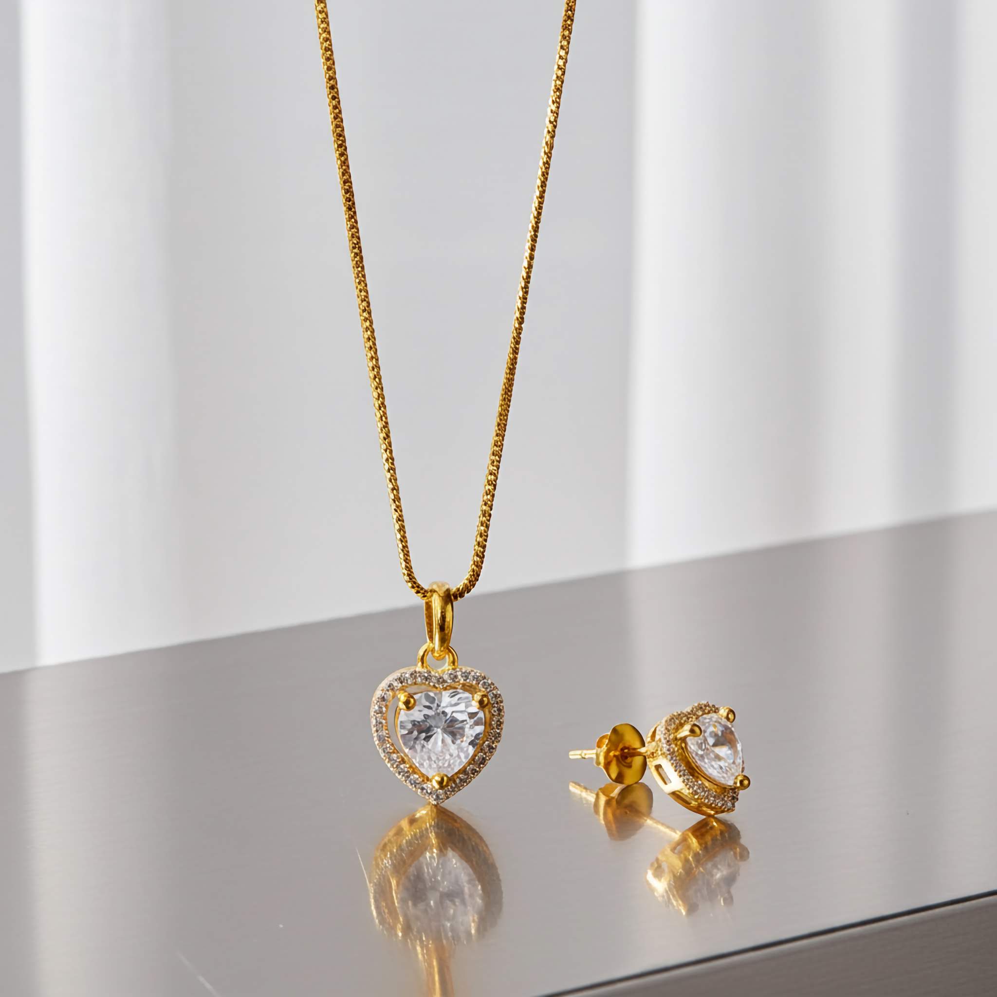 A Zirconia diamond 18k Gold plating heart-shaped necklace and earrings on a reflective surface with a light gray background