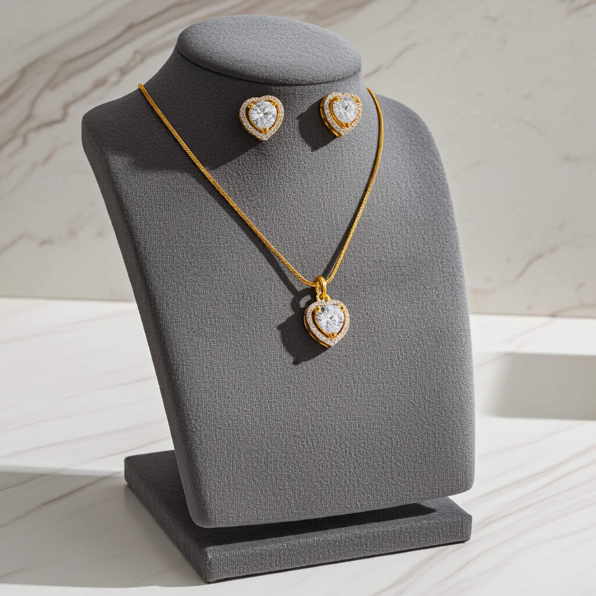 Jewelry set of Zirconia diamon with 18k gold-plated necklace and earrings on a gray stand against a light background