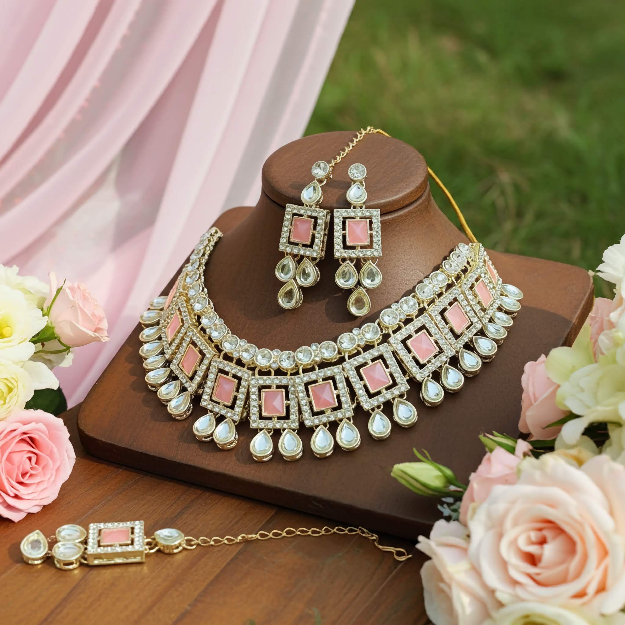 A Royal pink Kundan choker Jewelry set with necklace, earrings and tikka on a wooden stand with flowers around offered by LedeSaRa.