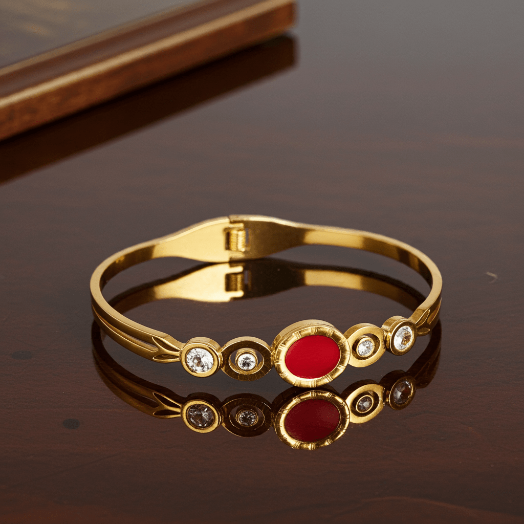 Gold bracelet with a red gemstone on a reflective surface