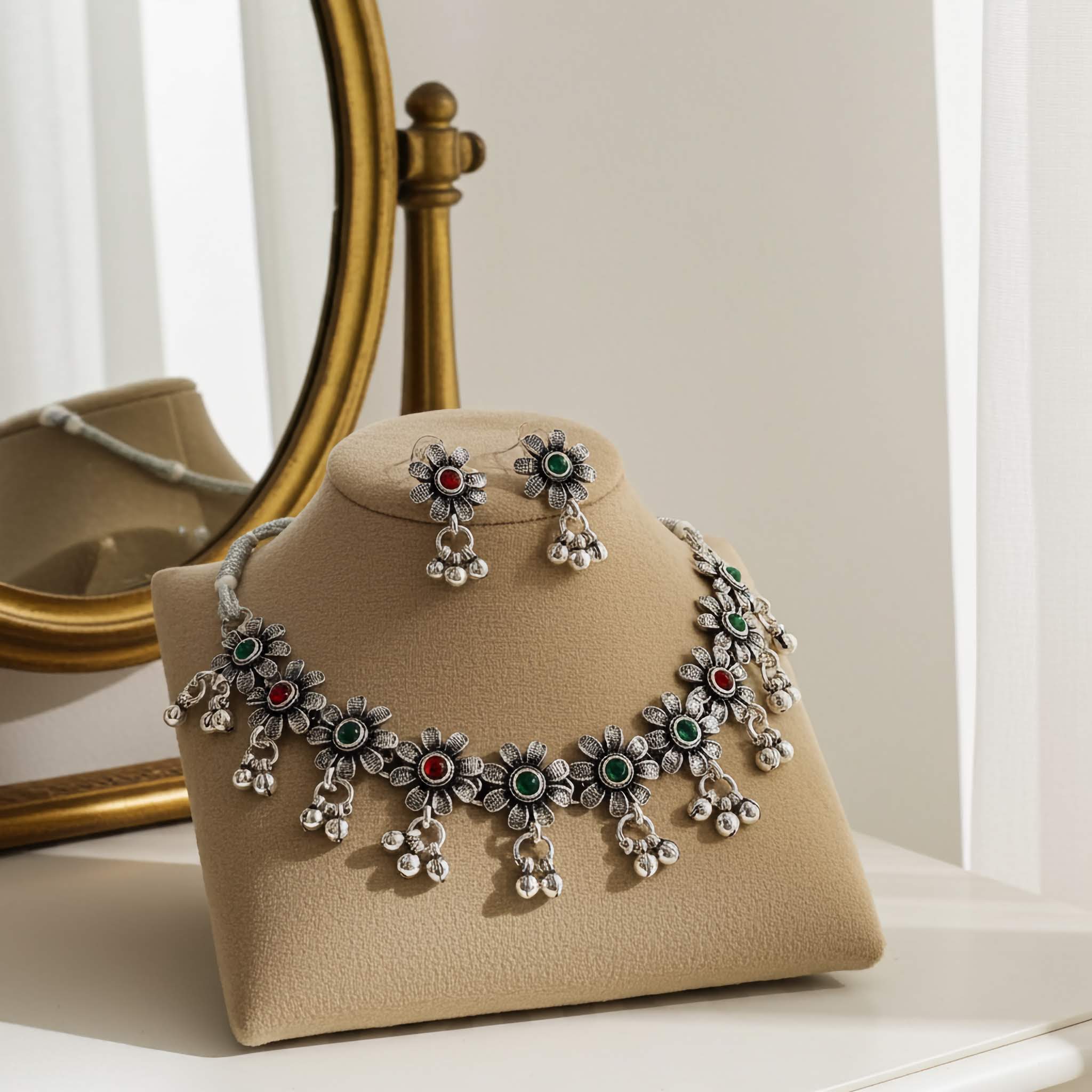 Silver necklace and earrings on a beige stand with a gold mirror in the background