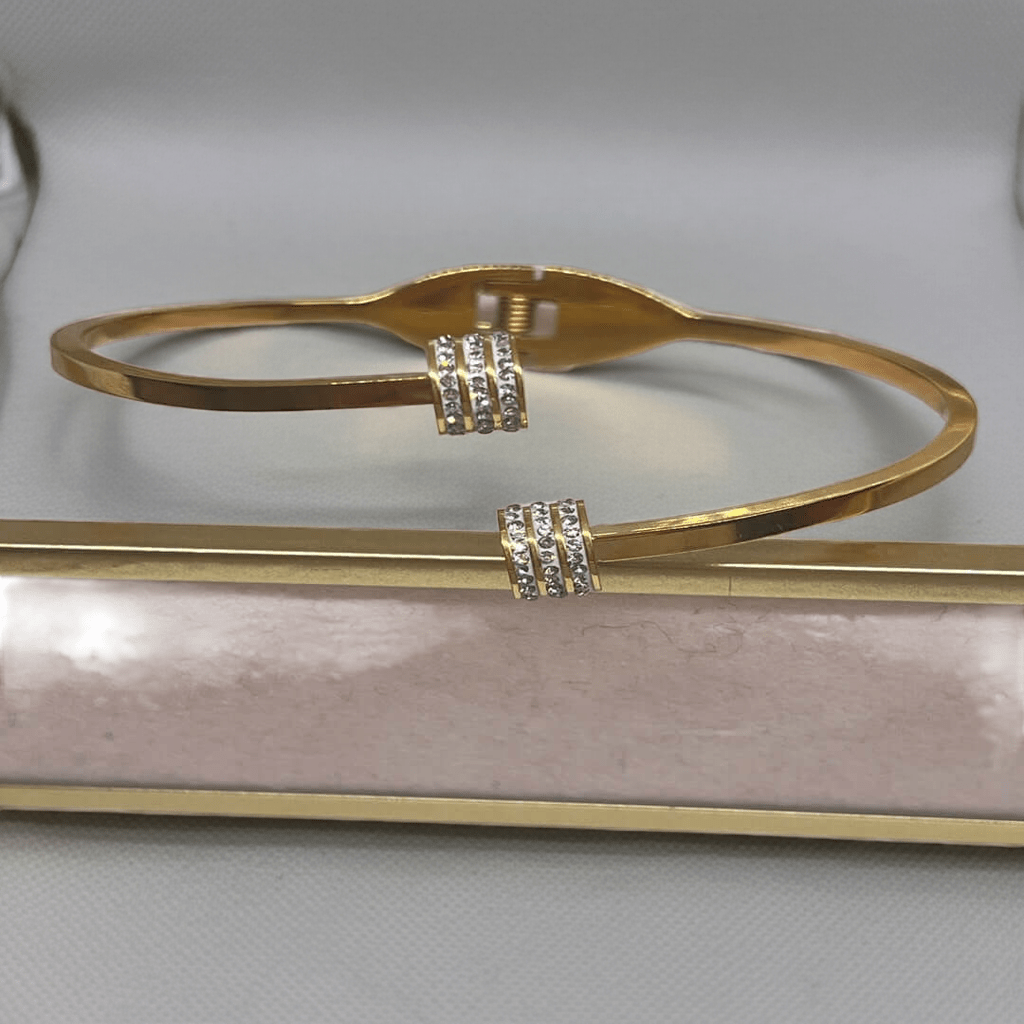 Gold bracelet with diamond accents on a light pink surface