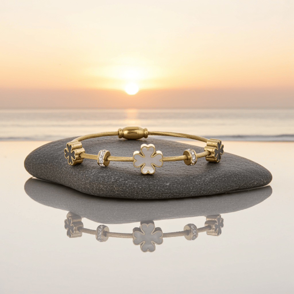 3 leaf charm bracelet with 18k gold plating  on top of a stone