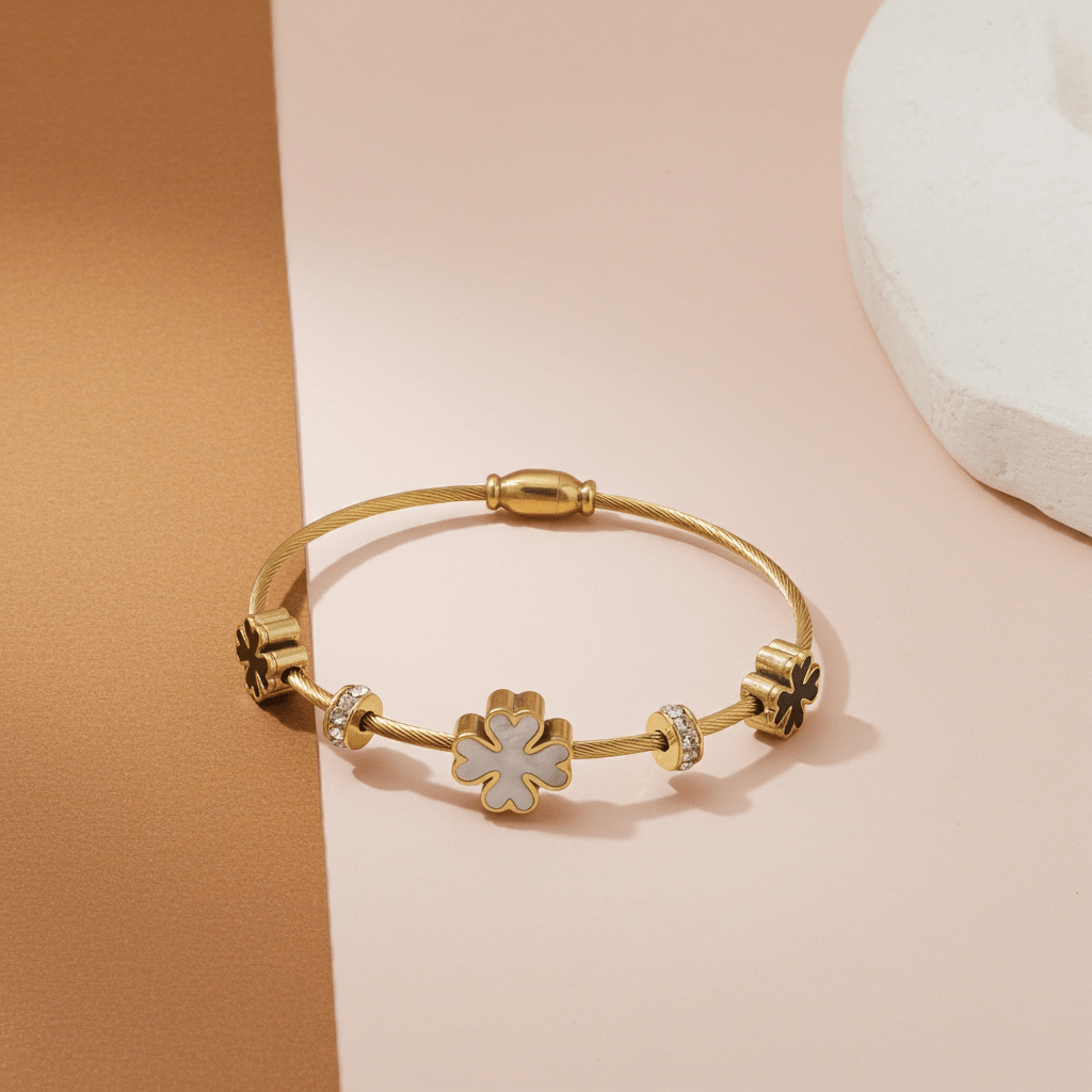 3 leaf charm bracelet with 18k gold plating  on a light pink surface