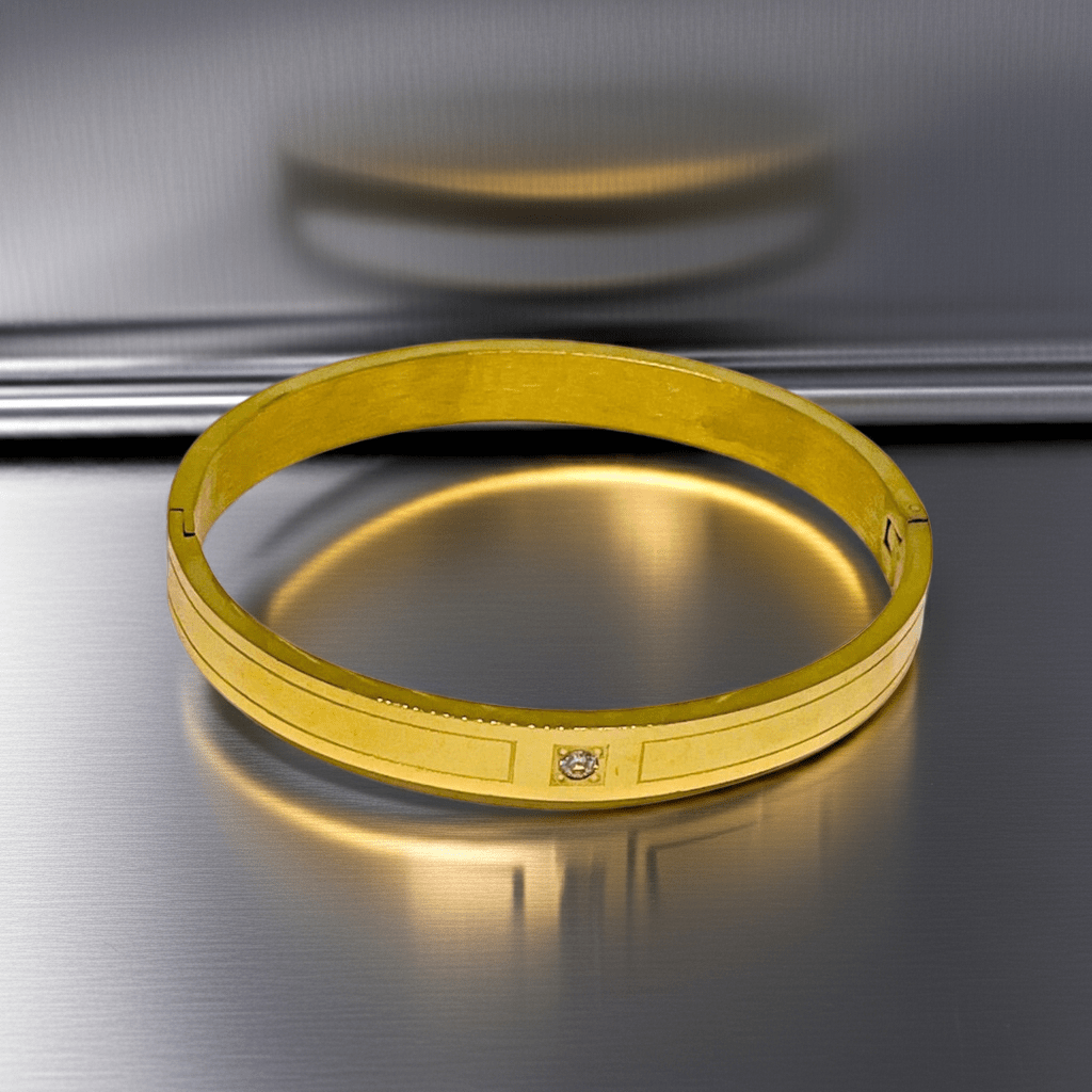 Gold bracelet on a reflective metallic surface