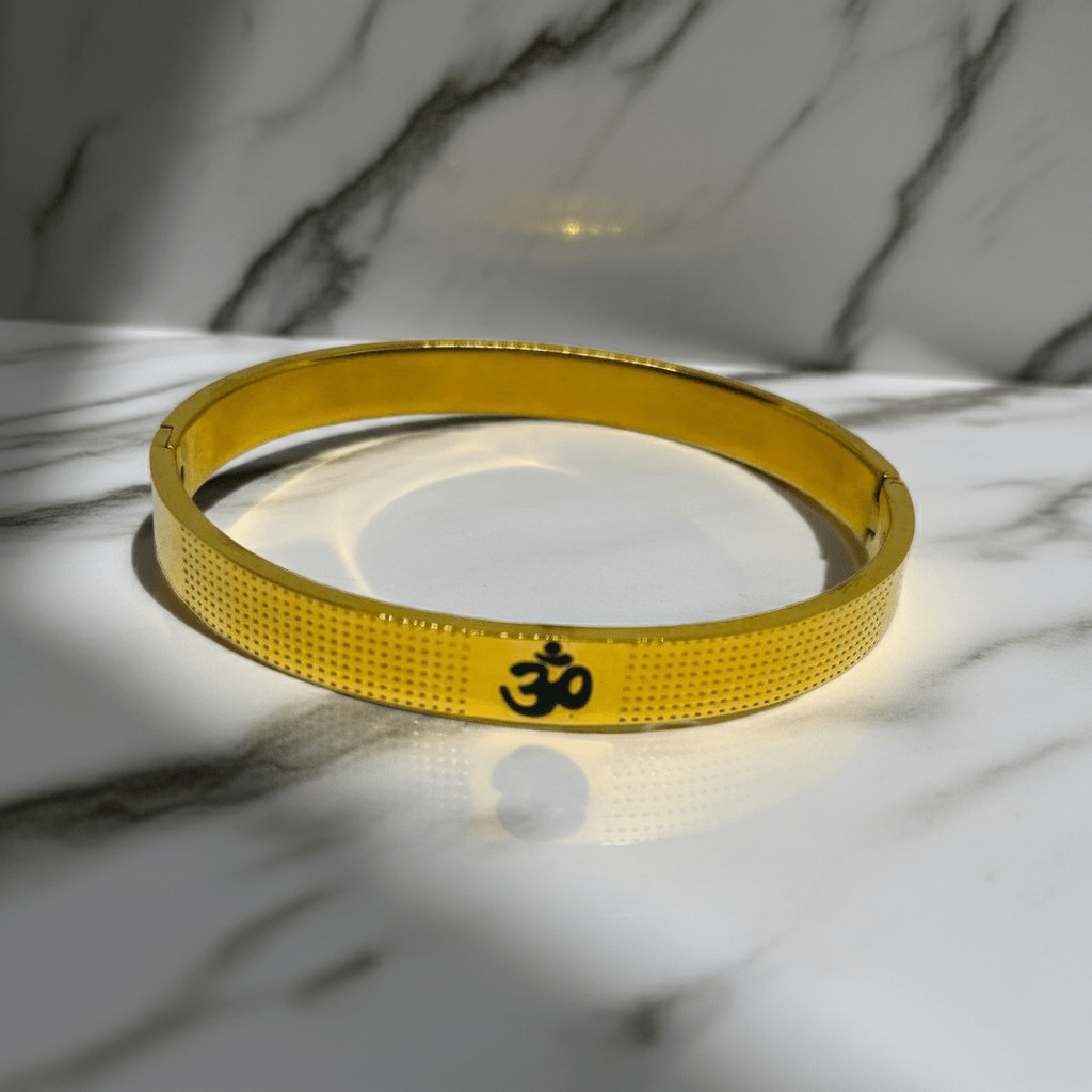 Gold bracelet with Om symbol on a marble surface