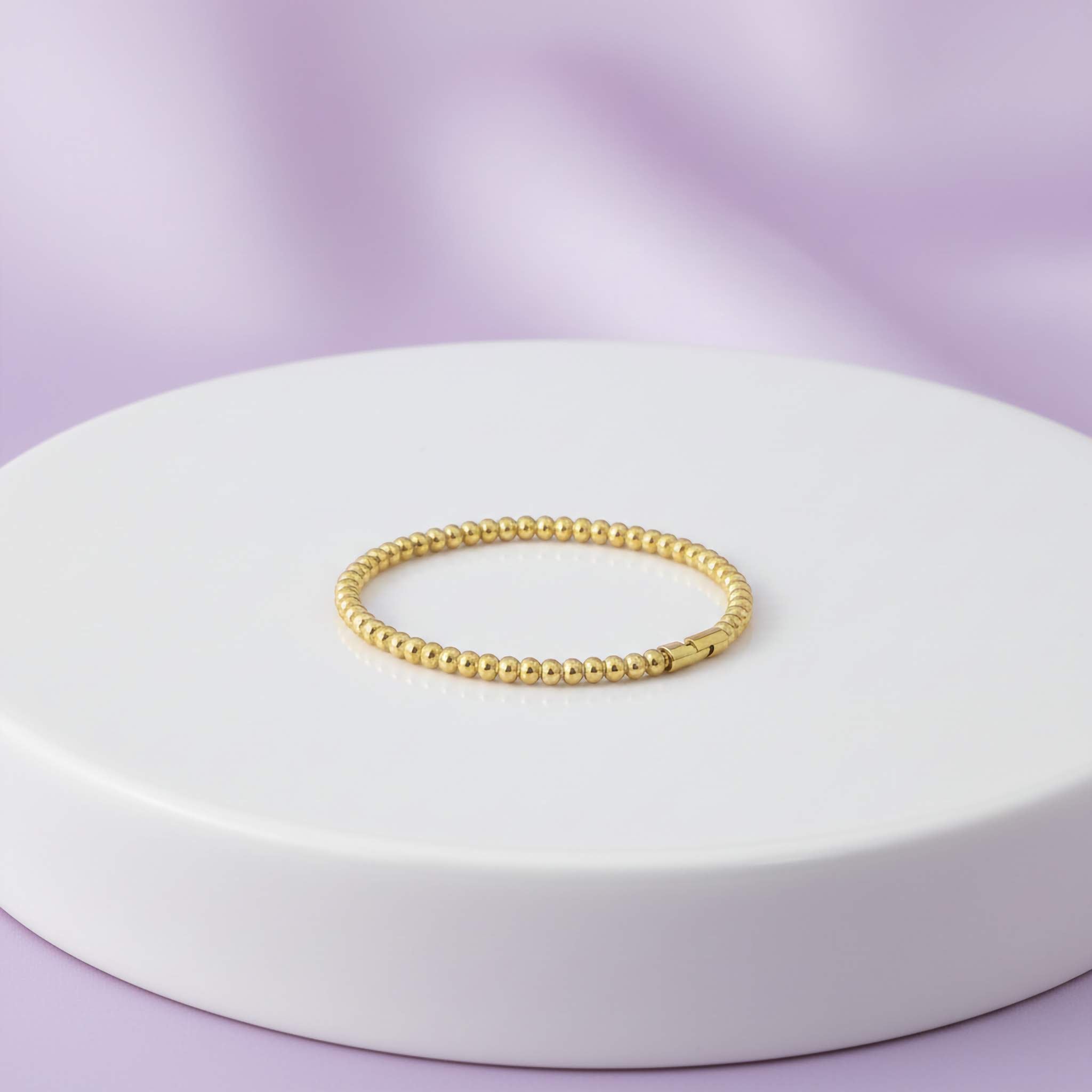 18k Gold bracelet beaded  on a white platform with a purple background