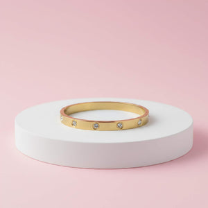 Gold plated cartier zirconia diamond bangle on a pink background