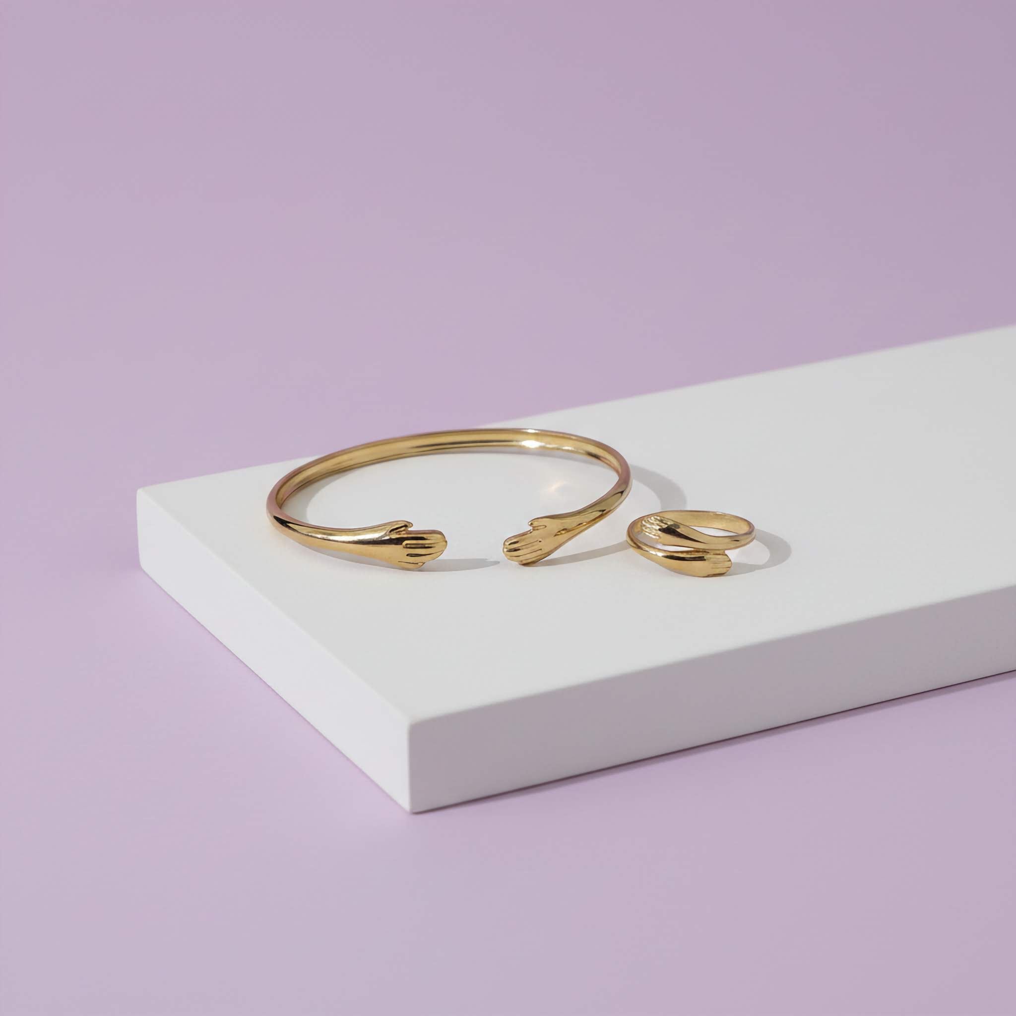 18k Gold plated bracelet and ring on a white platform with a light purple background