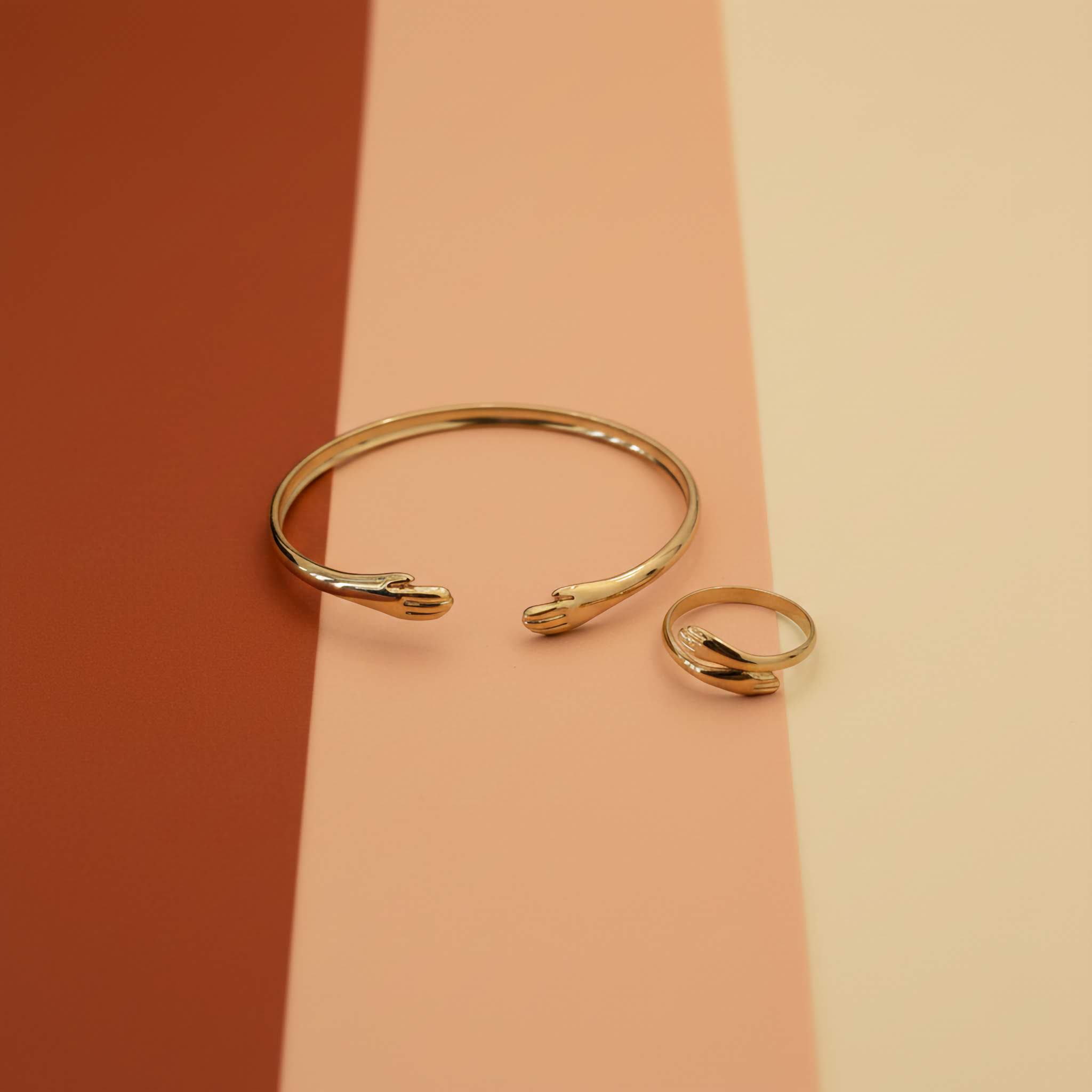 18k Gold plated bracelet and ring set on a two-tone pink background