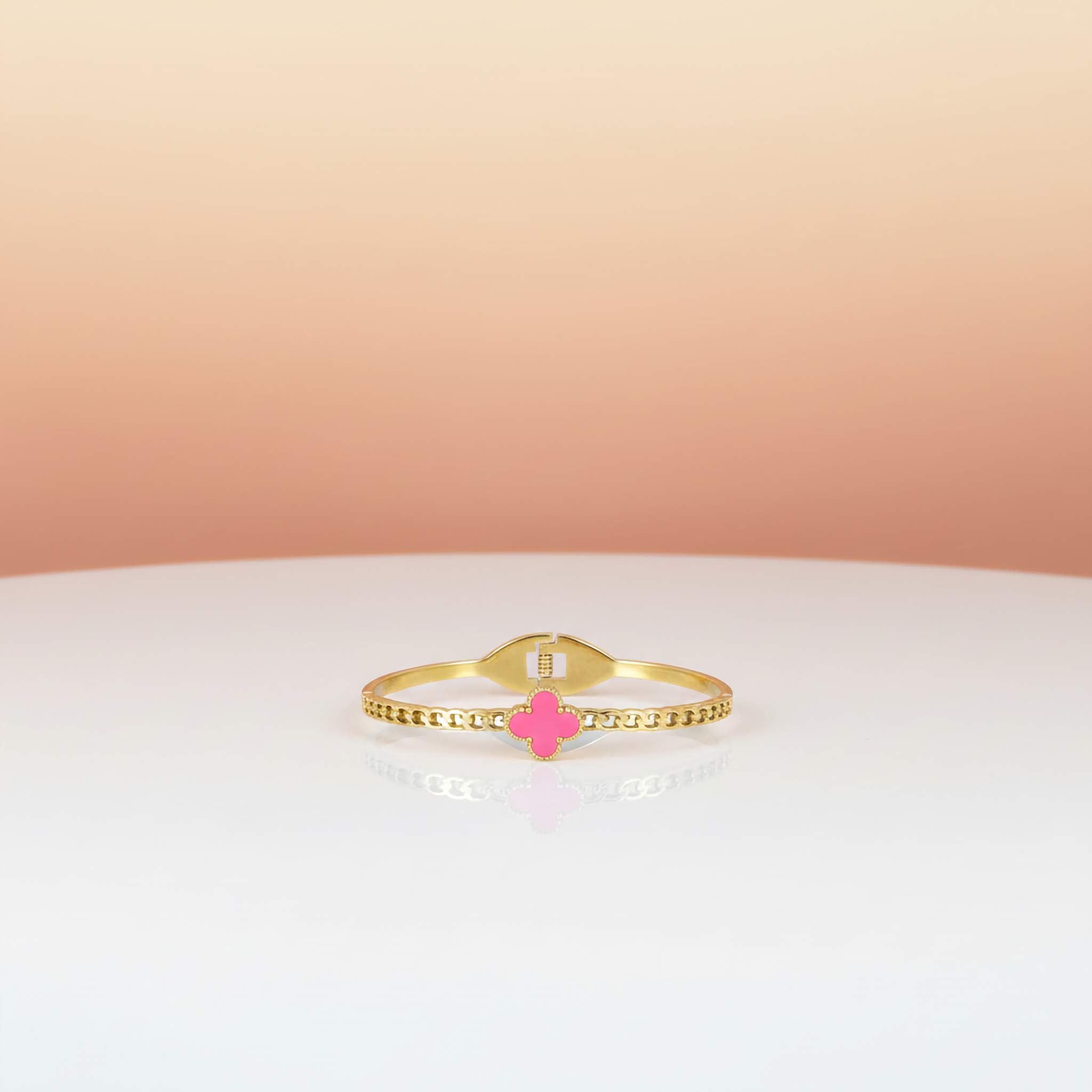 18k Gold plated bracelet with a pink clover charm on a gradient background