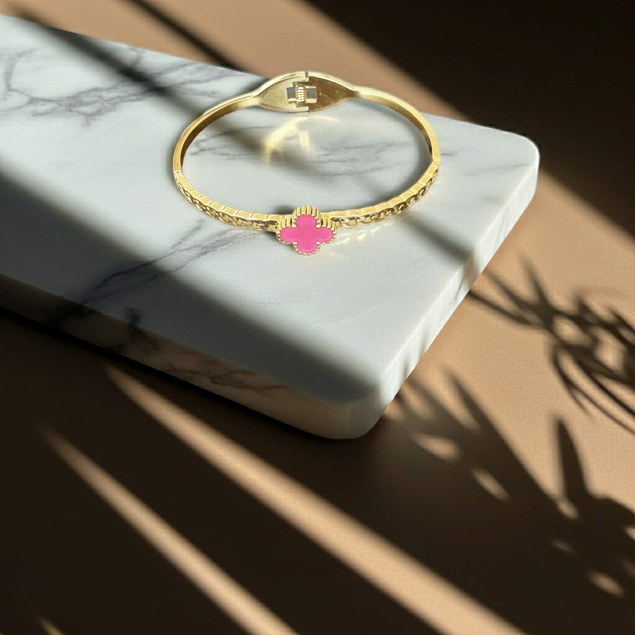 18k Gold plated bracelet with a pink clover charm on a stone background