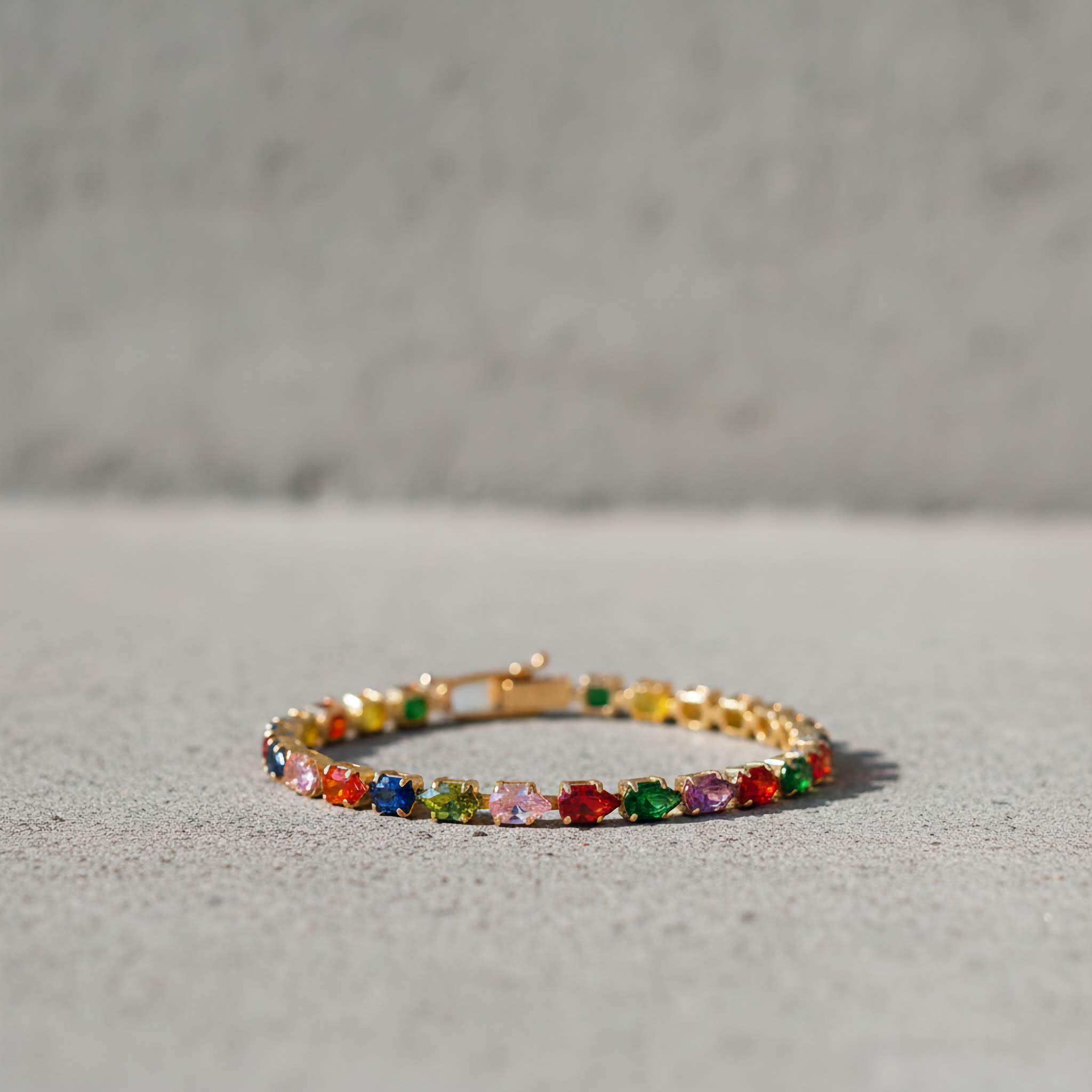 18k gold plated Multi-coloured gemstone tennis bracelet on a gray surface